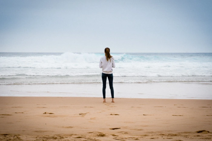 woman standing near seashore during daytime on sand beach 2k
