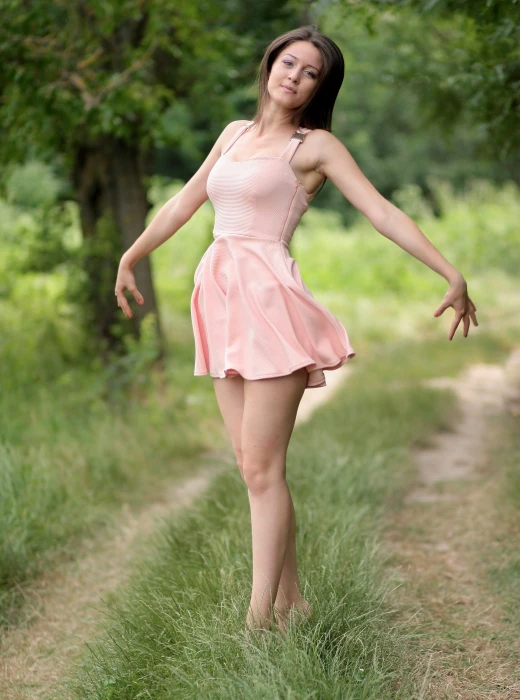 woman wearing pink sleeveless mini dress standing on green grass 2k