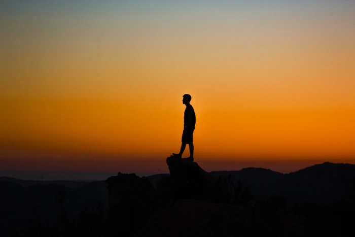 silhouette of man during sunset standing on rock cliff 2k 4k 5k