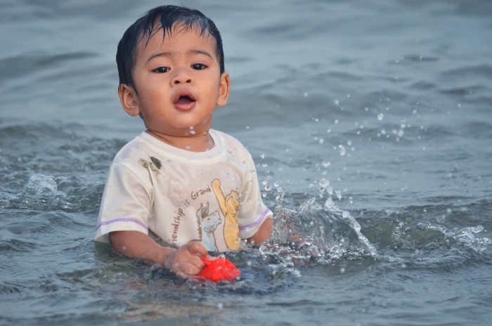 boy swimming on body of water during daytime child sea wave 2k 4k 5k