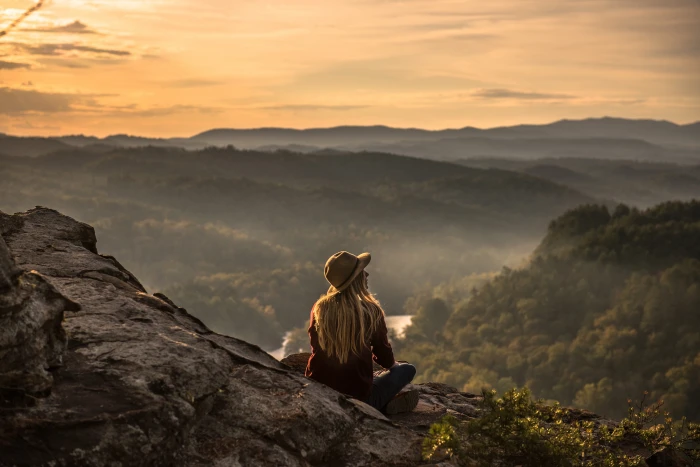 A woman wearing a hat sits on area with mountains people girl 2k 4k 5k