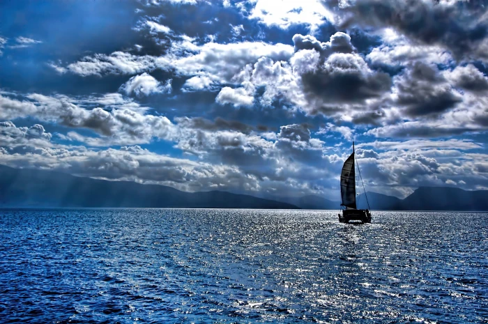 black sailing boat under cumulus clouds on body of water Relocation 2k