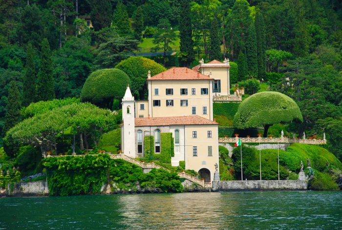 beige and white house near body of water lago di como italy 2k