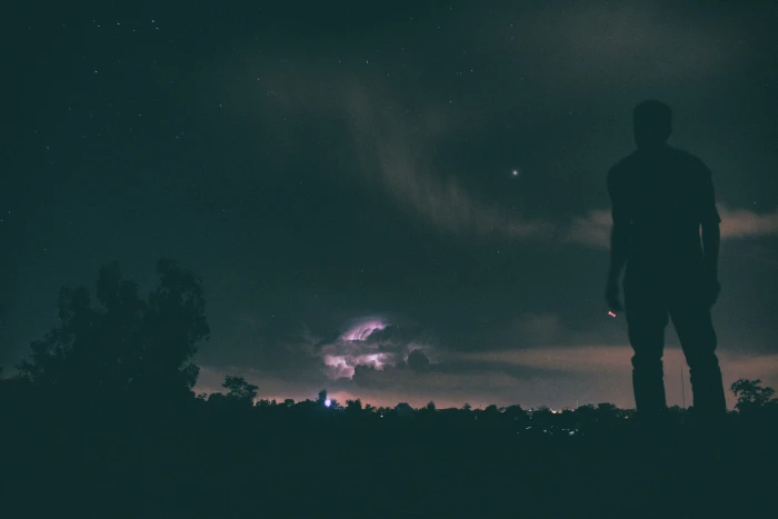 silhouette of man standing under night sky on ground looking at during nighttime 2k 4k 5k