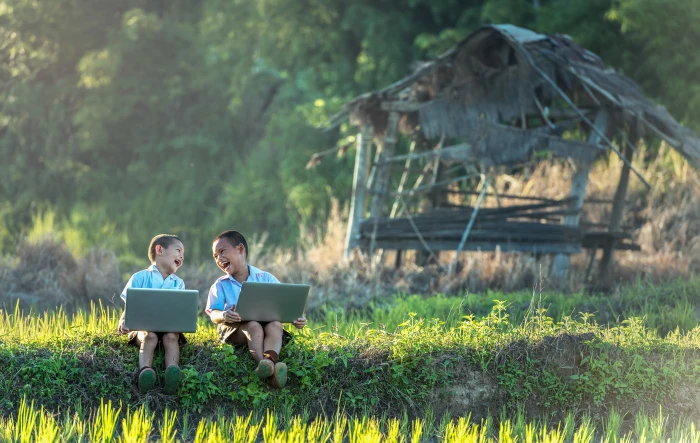 two toddlers sitting on grass field while holding gray laptops 2k 4k 5k