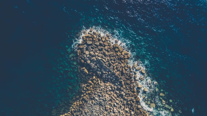 aerial view photography of brown rocks beside ocean seashore 2k 4k 5k