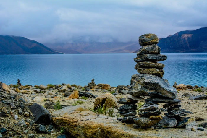 gray rocks stacks on brown surface balance stone near body of water 2k 4k 5k