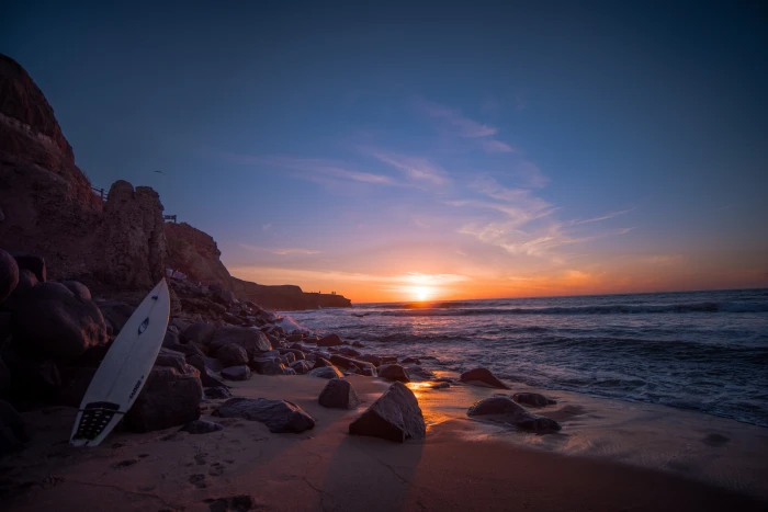 white surfboard leaning on rock near water at sunset Time San 2k 4k 5k