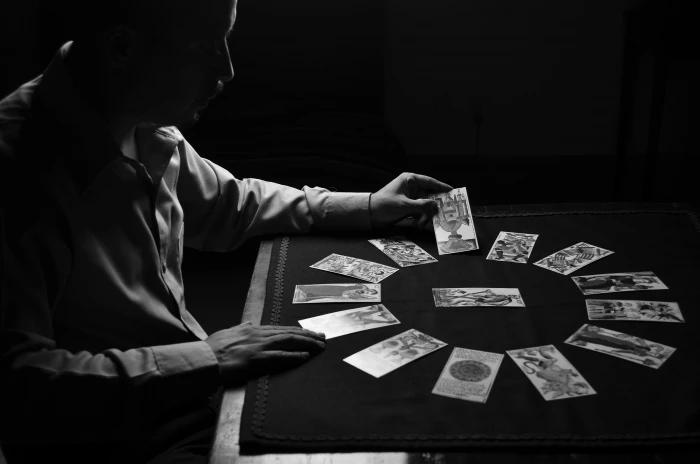 person in dress shirt front of table with cards mystic letters 2k 4k