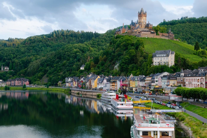 brown castle on top of mountain under with multicolored painted buildings near body water 2k 4k 5k
