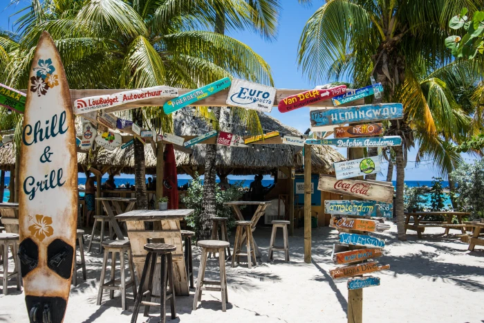 photo of signage near store and ocean willemstad beach tropical 2k 4k 5k