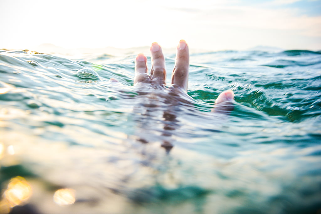 tilt shift lens photography of persons hand above body water and his under the