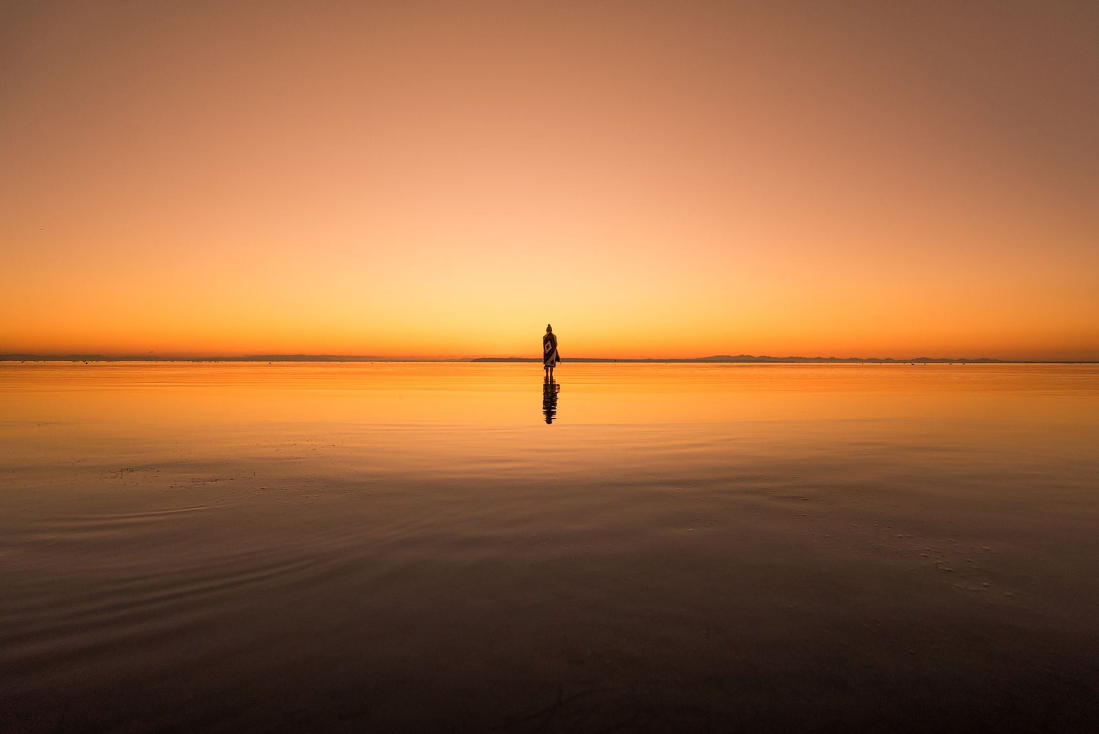 calm body of water silhouette photo person standing above 2k