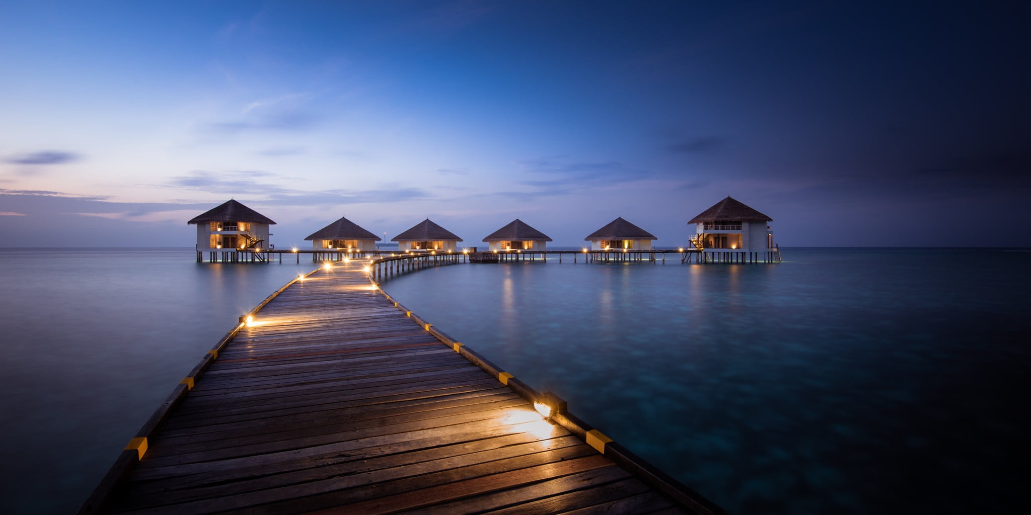 brown wooden dock and cottages Maldives resort artificial lights 2k