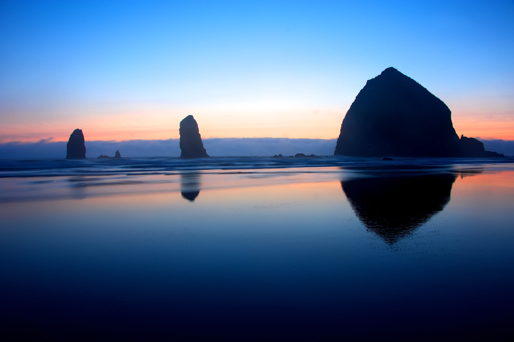 calm body of water under blue sky photo Blue hour Haystack Rock 2k