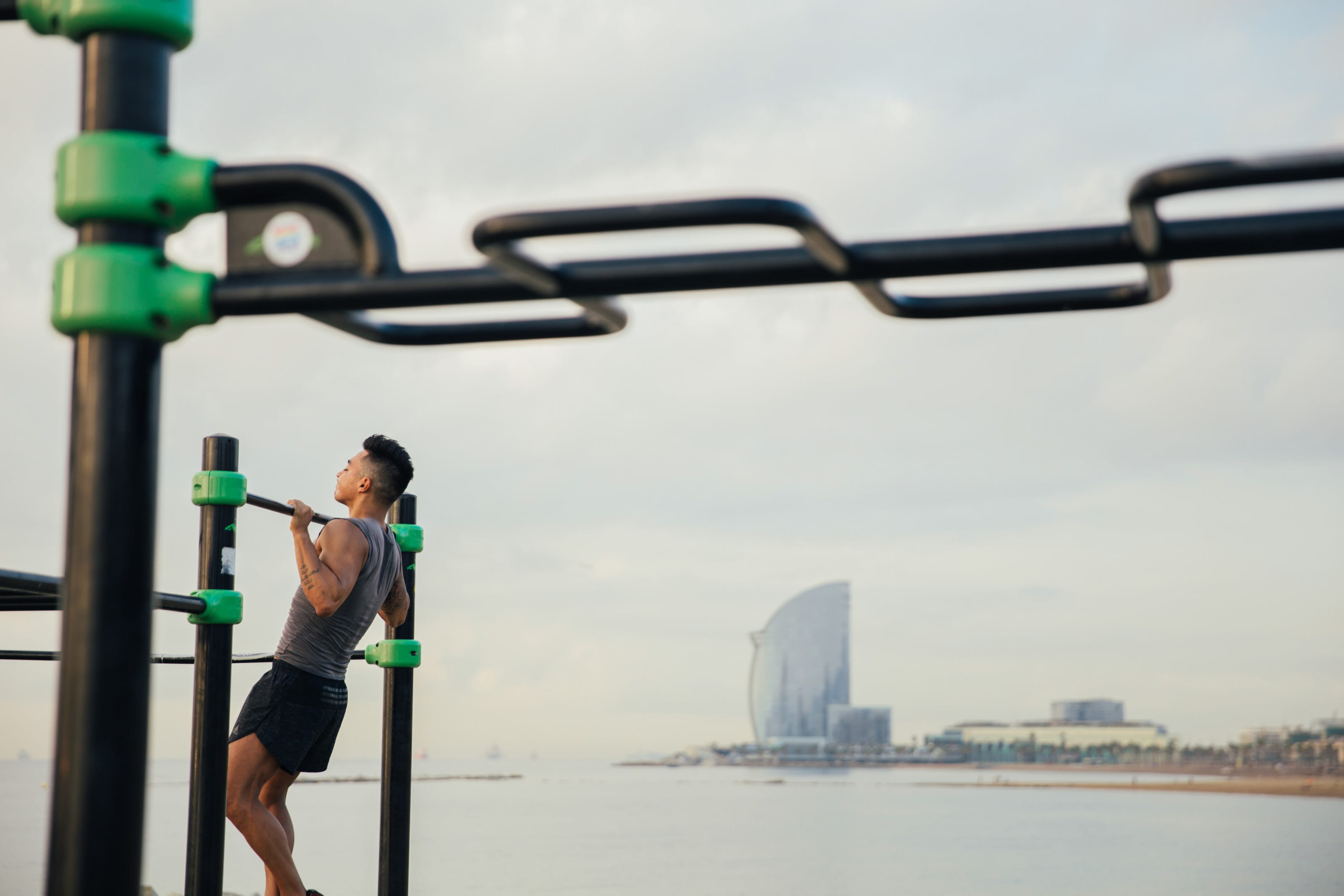 A young Asian man doing chin up exercise on the beach Adult 2k