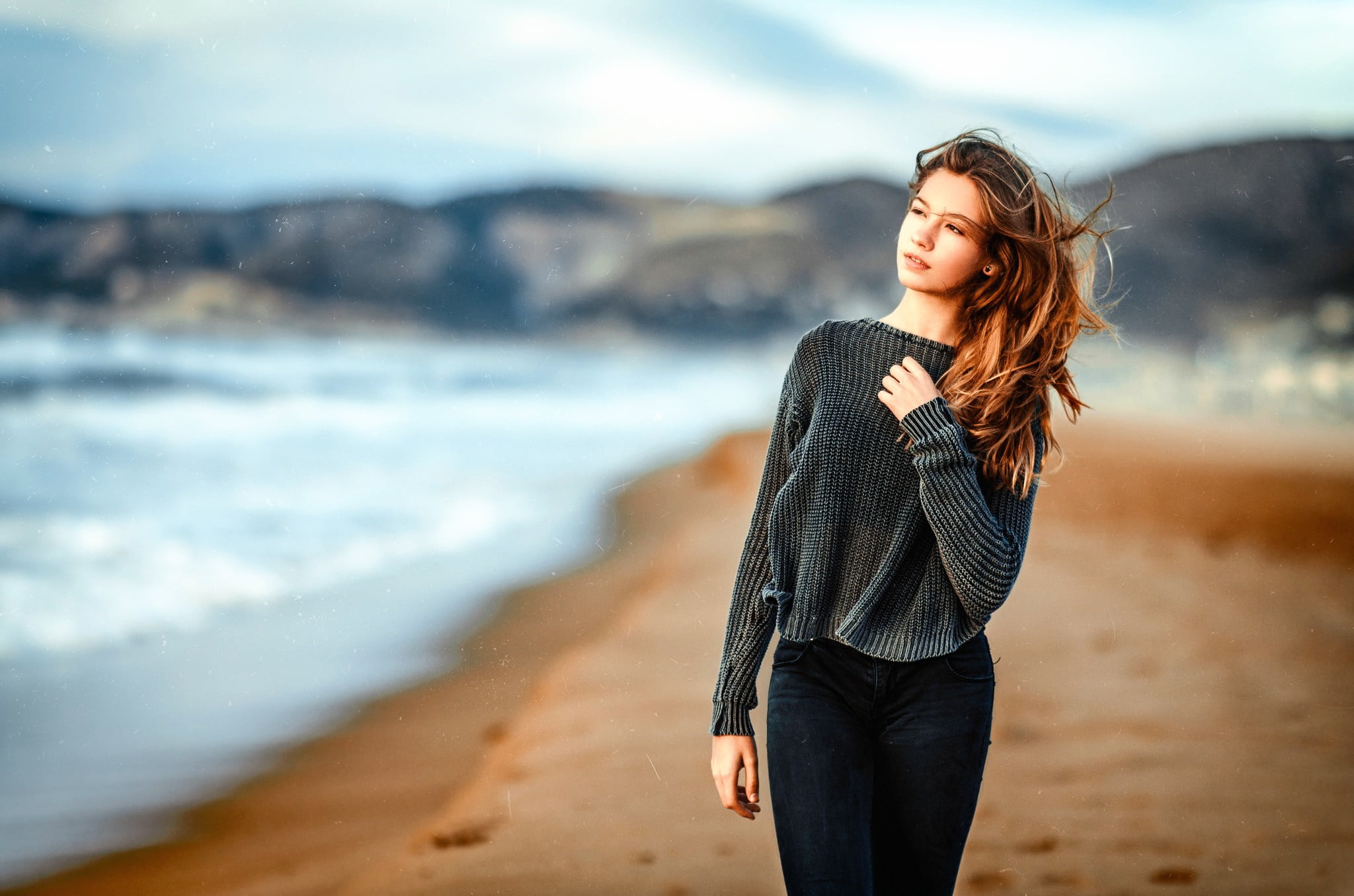 woman in gray sweater standing near shoreline during daytime 2k