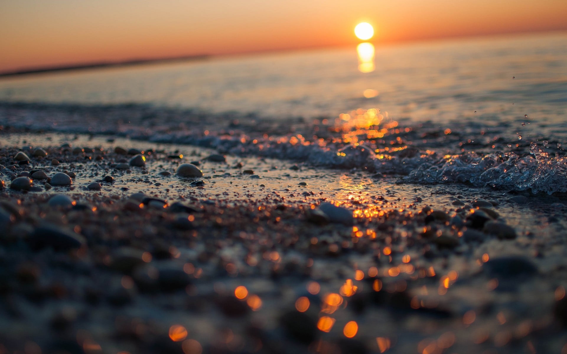 pebble stone and body of water seashore photo taken during golden hour 2k