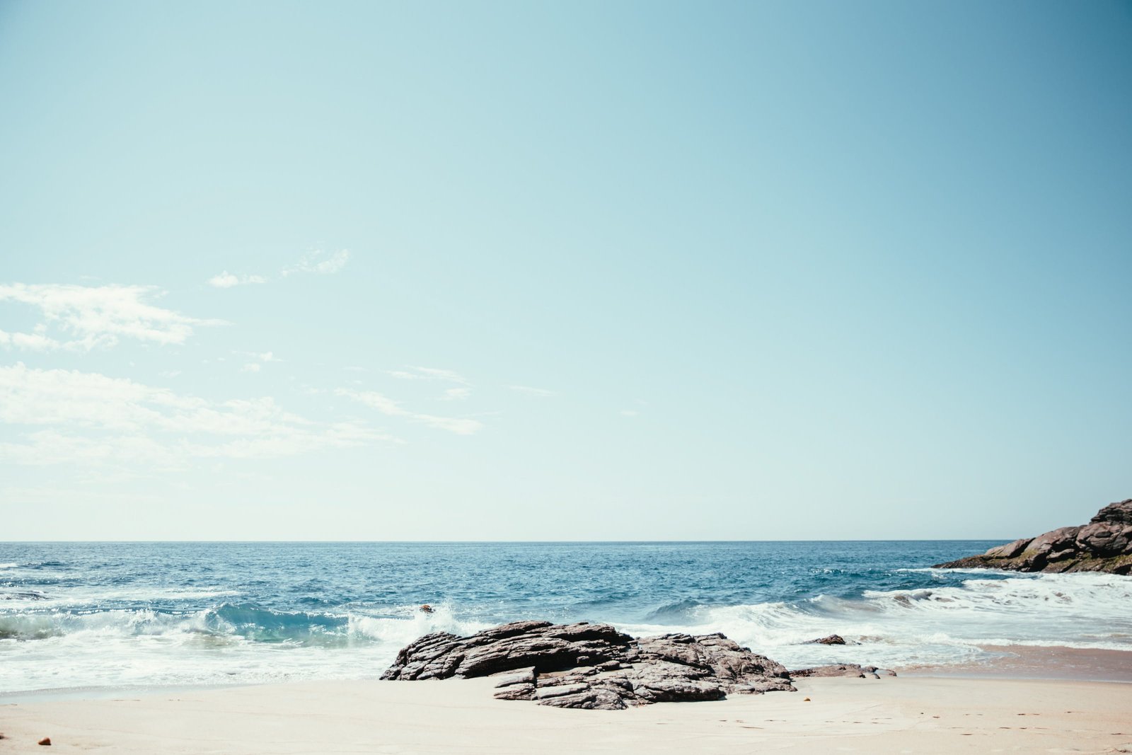 A rocky beach in sunlight with horizon the background Clear Sky 2k