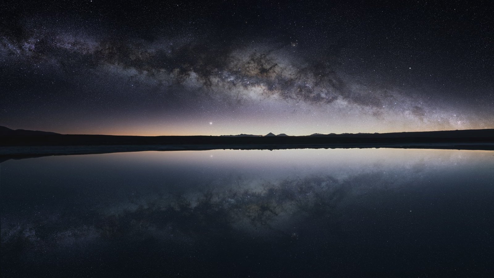 silhouette of mountain in front body water under dark sky 2k
