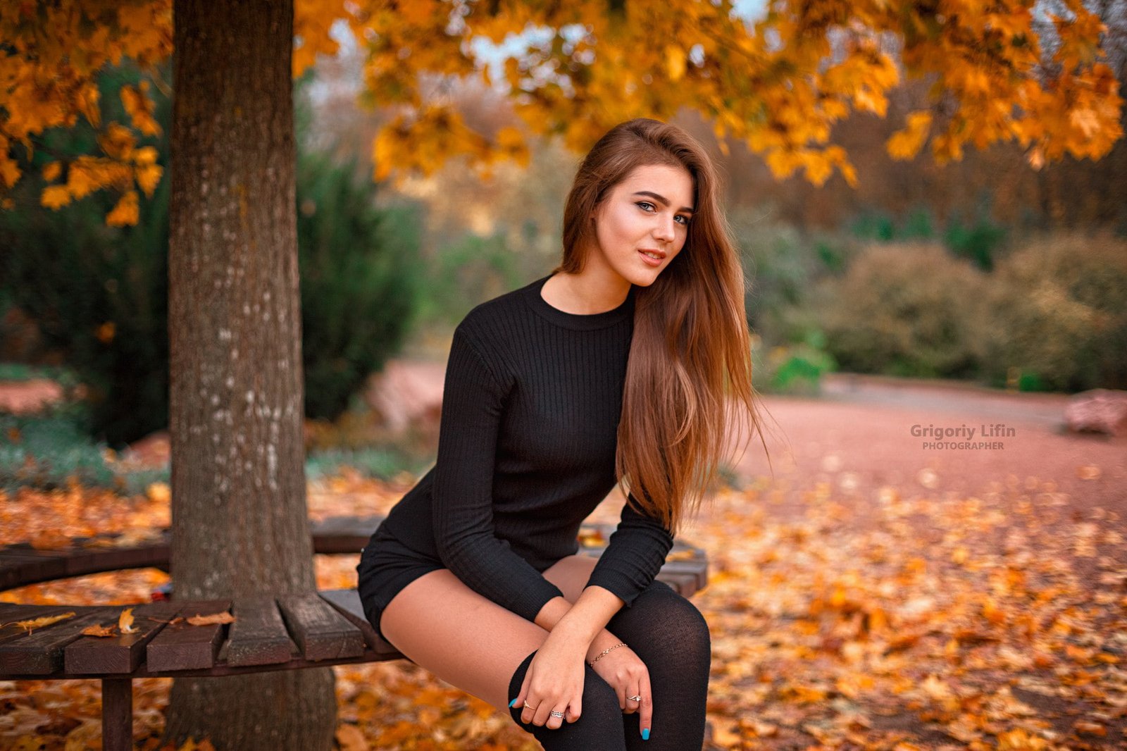 women's black long sleeved dress woman sitting on a wooden bench under tree 2k