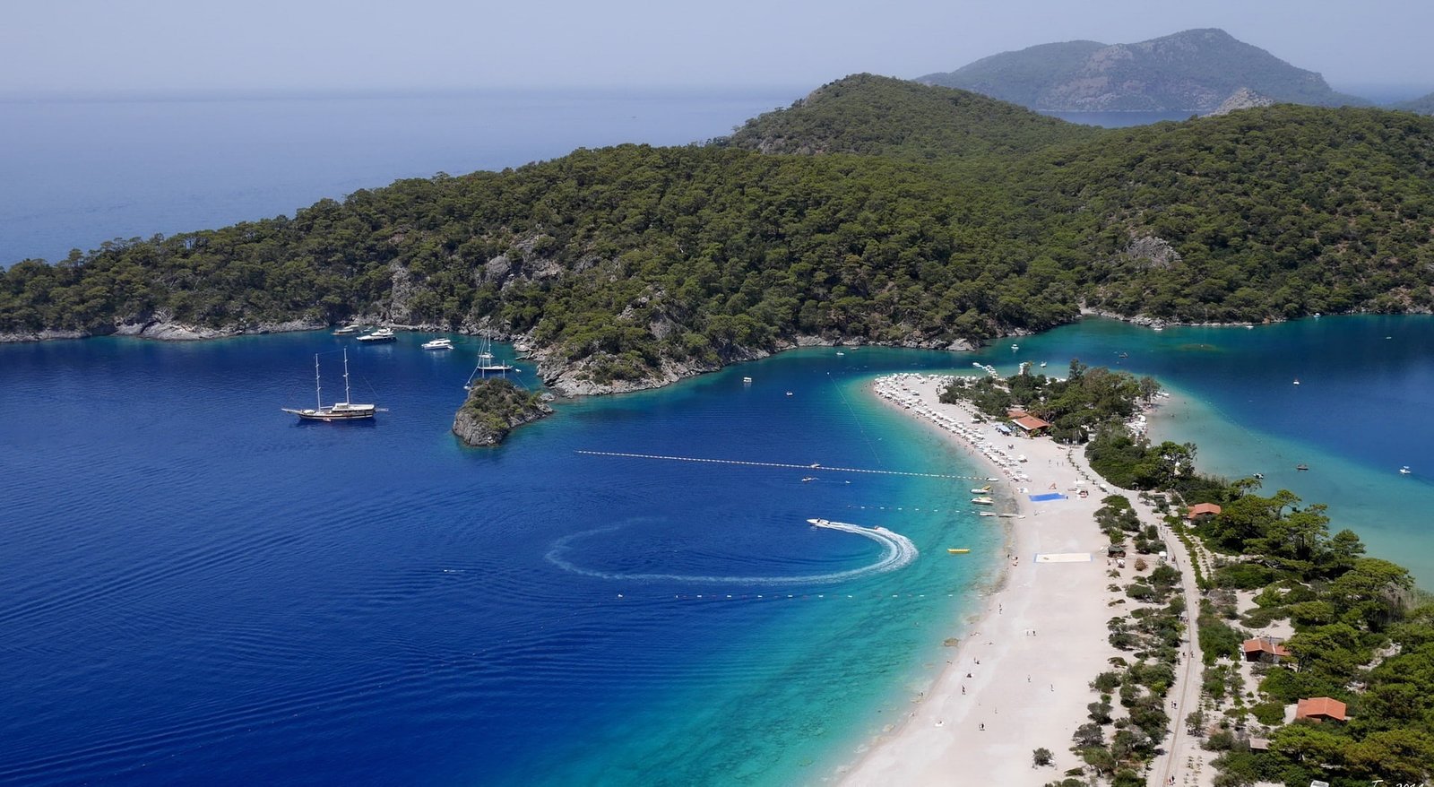 Blue Lagoon body of water and island surrounded by green leaf trees 2k