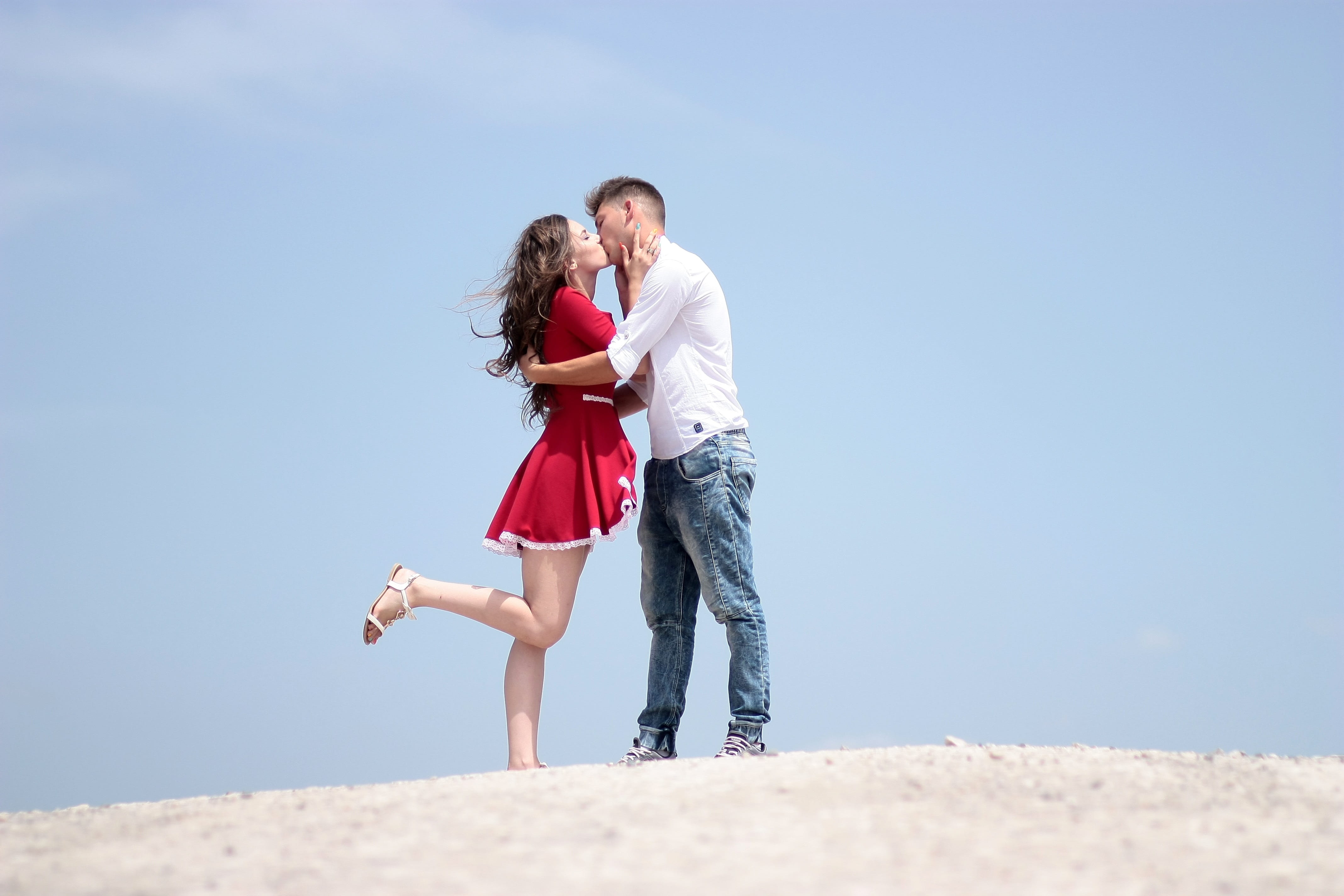 man and woman kissing while standing on white surface during daytime 2k 4k