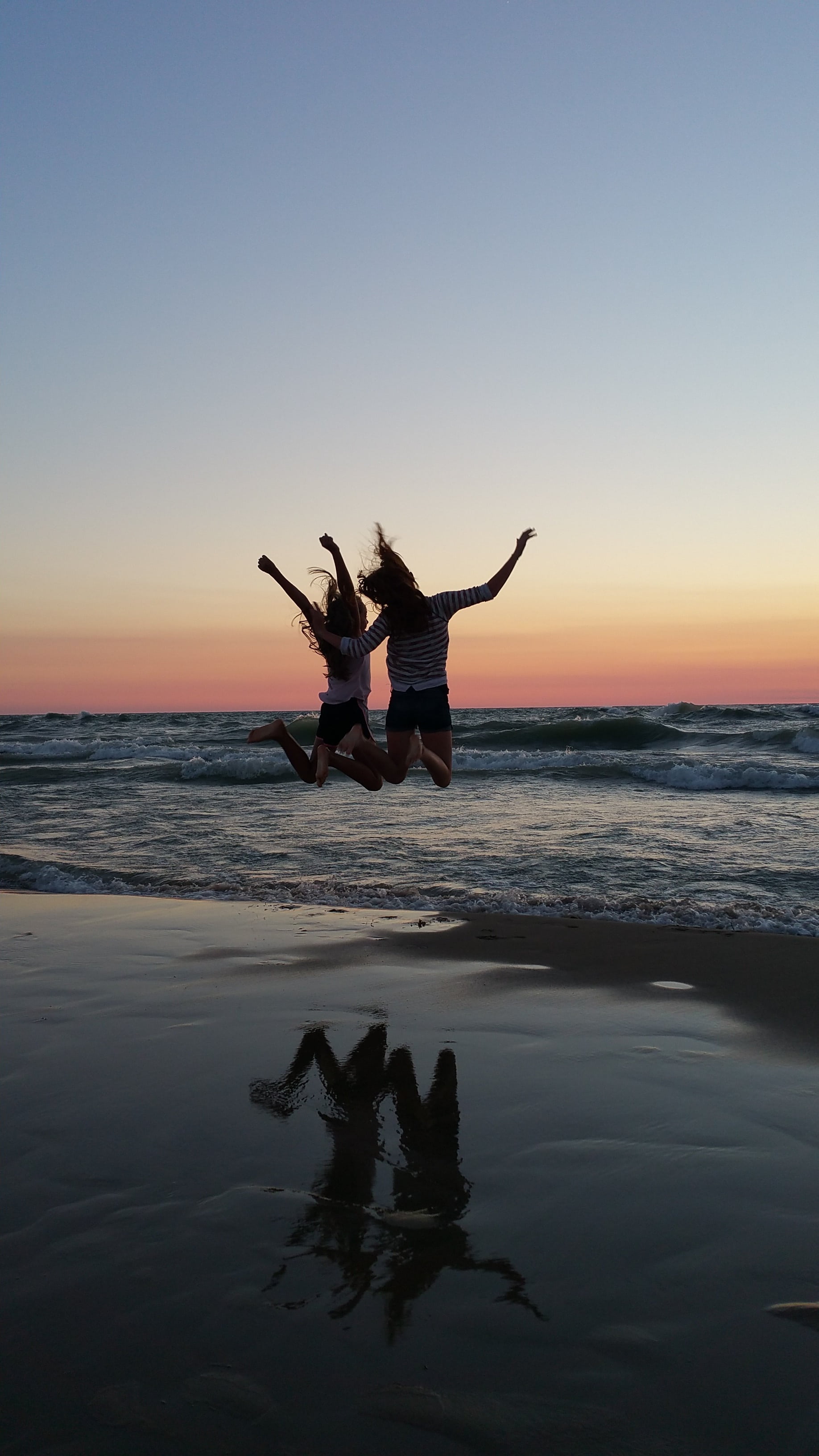 two women jumping on seashore best friends sunset beach cheer 2k