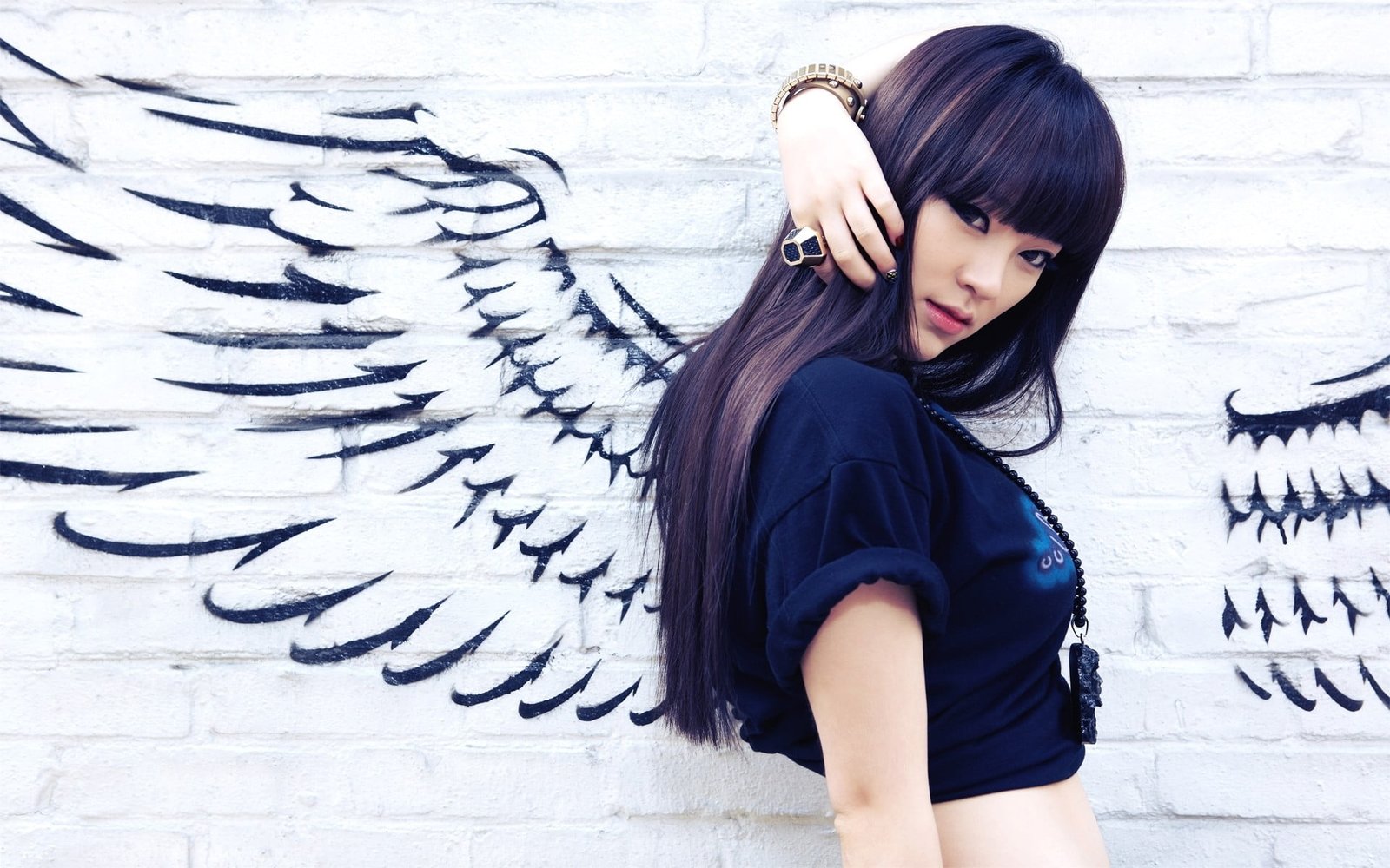 woman wearing black shirt while taking selfie behind painted wings in wall 2k