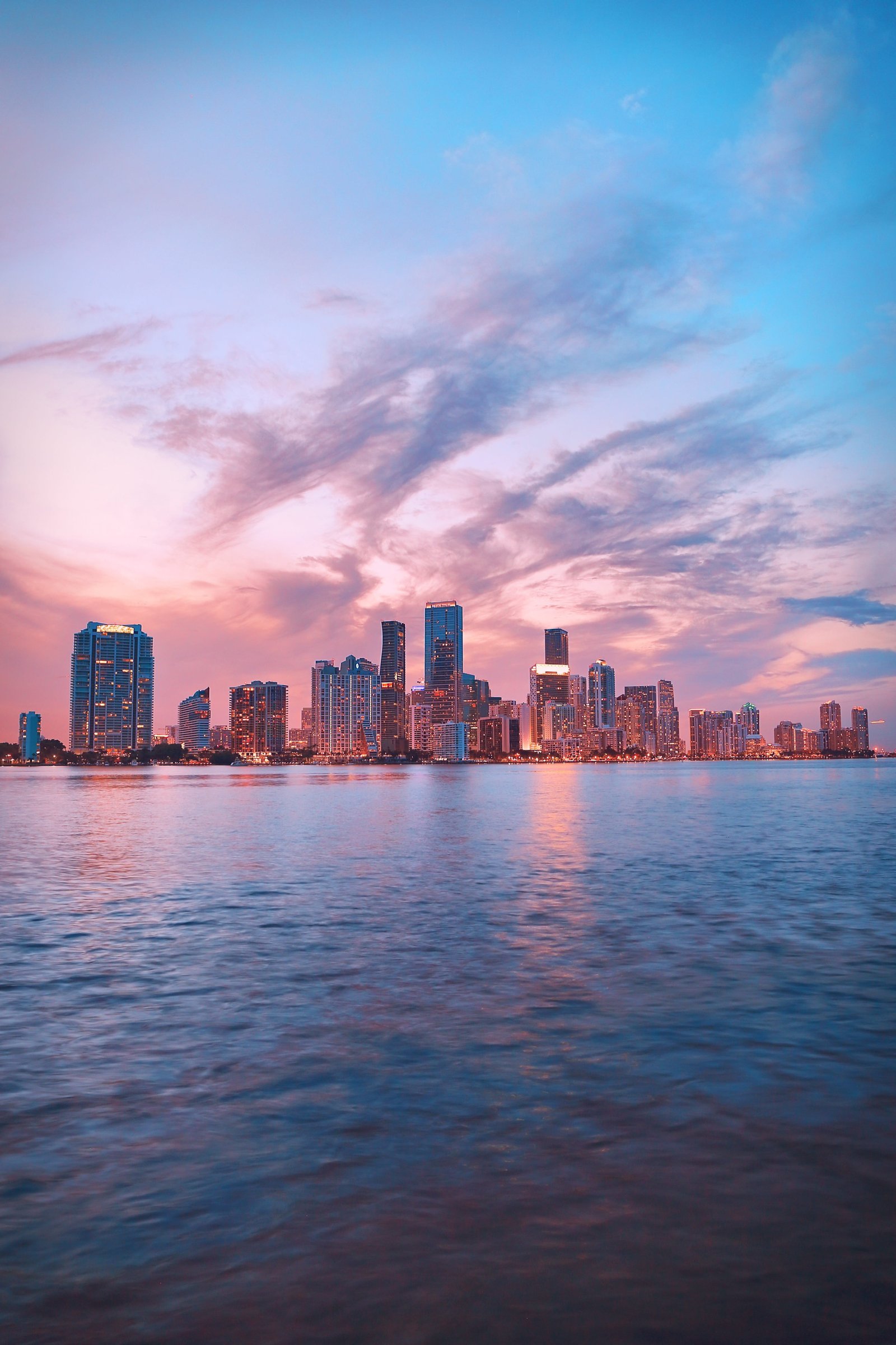 body of water near city high rise buildings skyline ocean 2k 4k