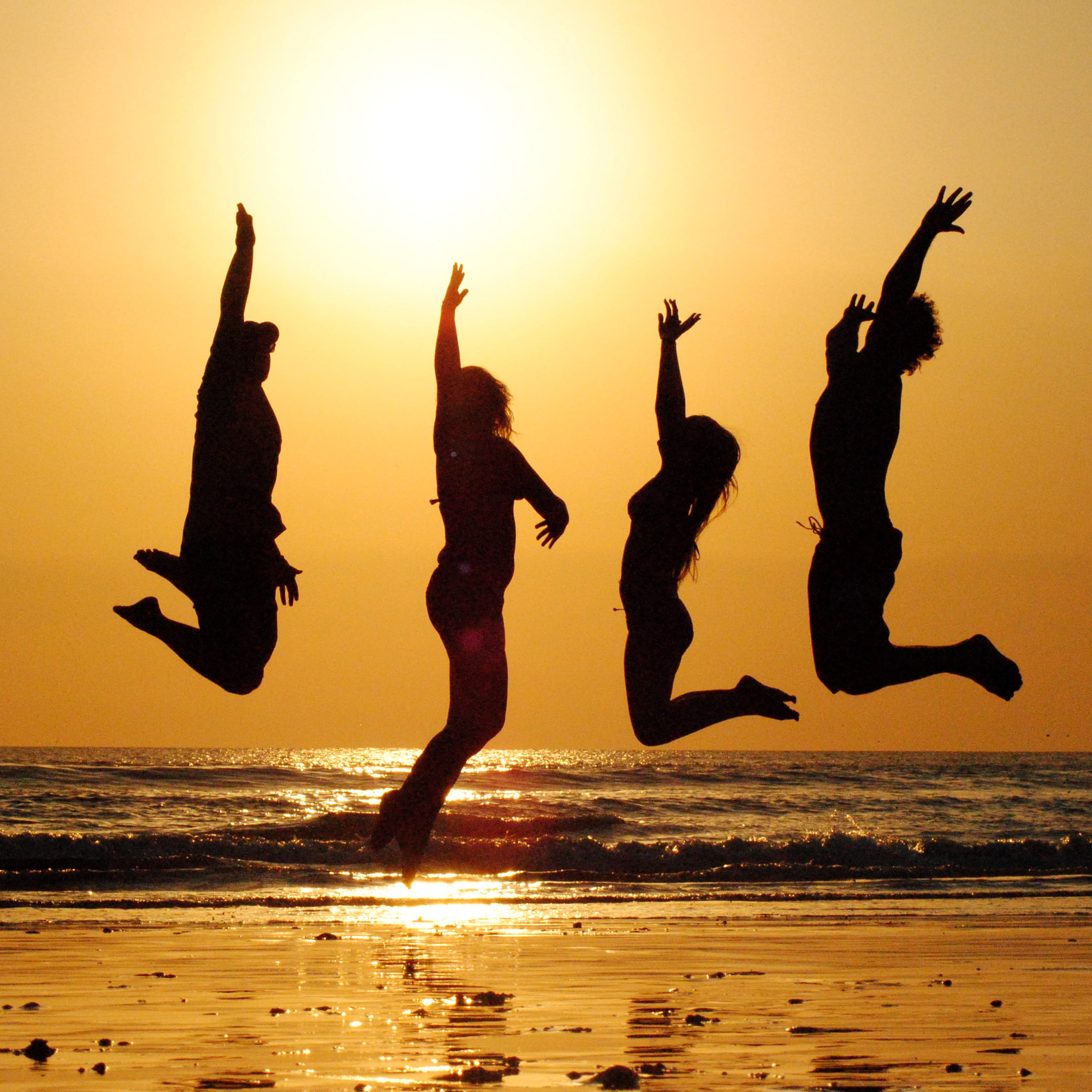 silhouette of four people jumping sunset beach group friends 2k