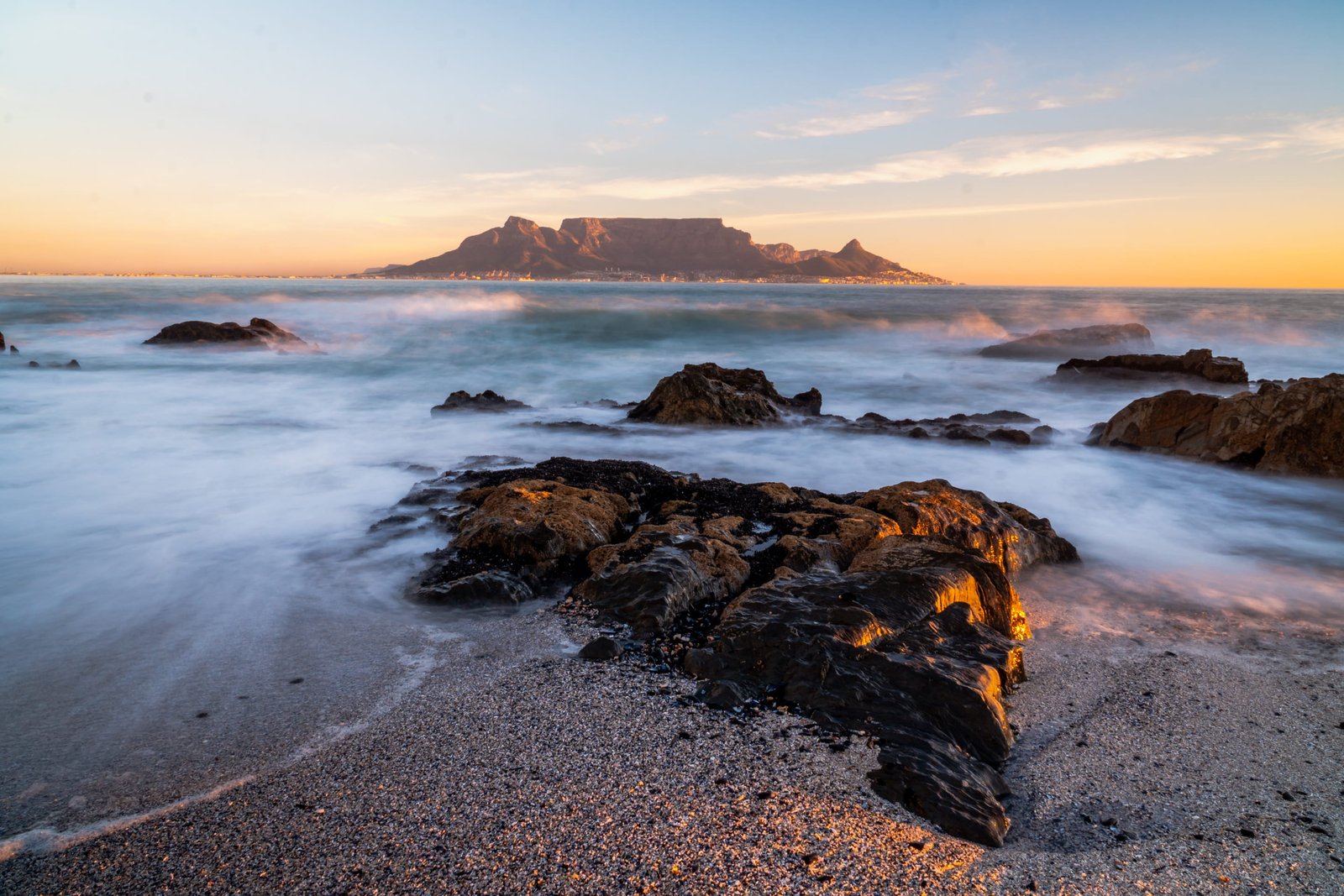 water splashing on shore rocks overlooking island at the horizon 2k