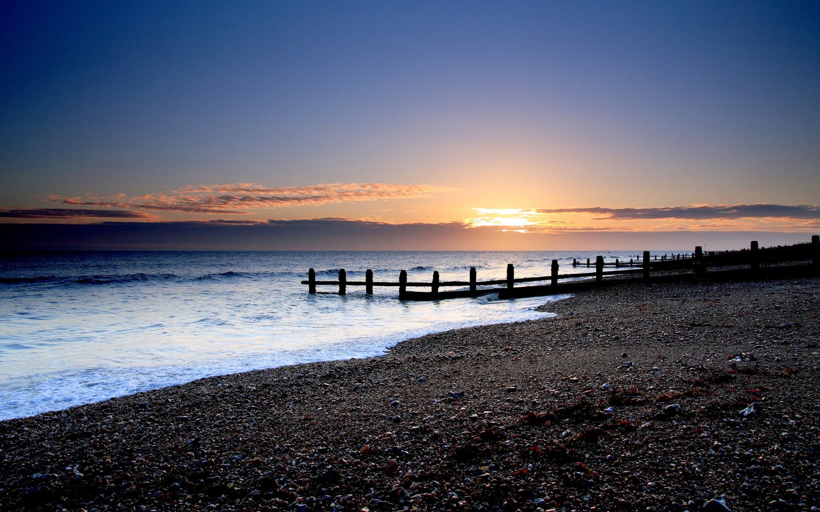 brown dock beside black sand at sunset beach sky sunlight 2k