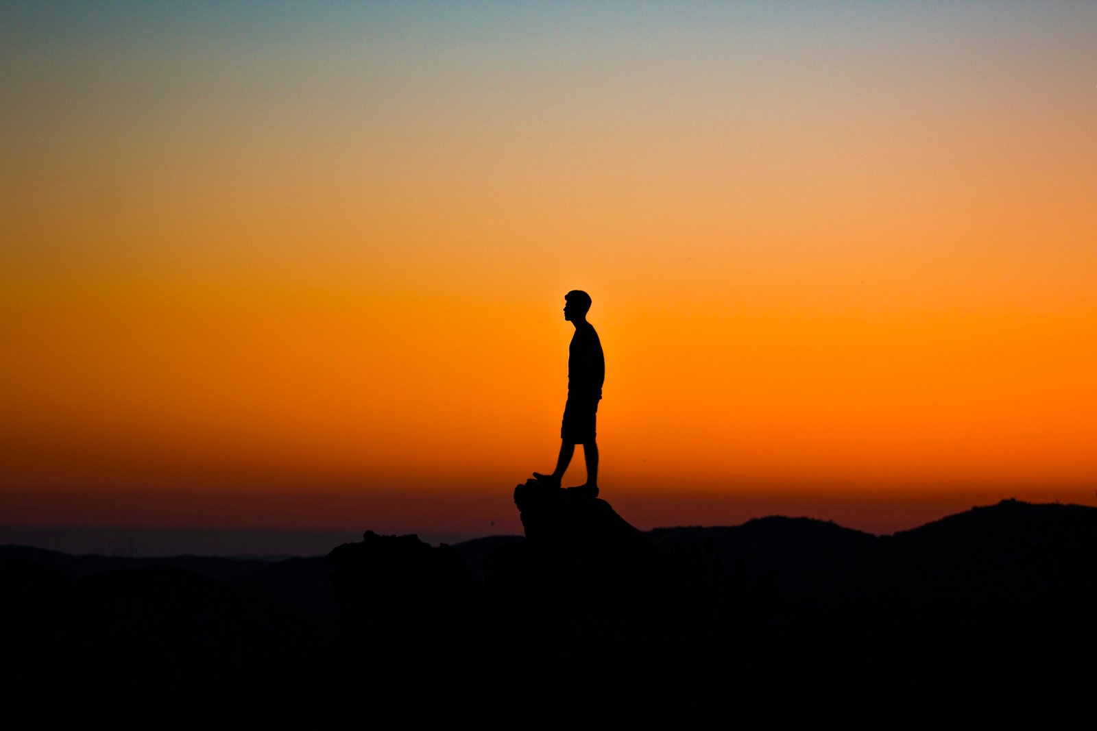 silhouette of man during sunset standing on rock cliff 2k 4k 5k