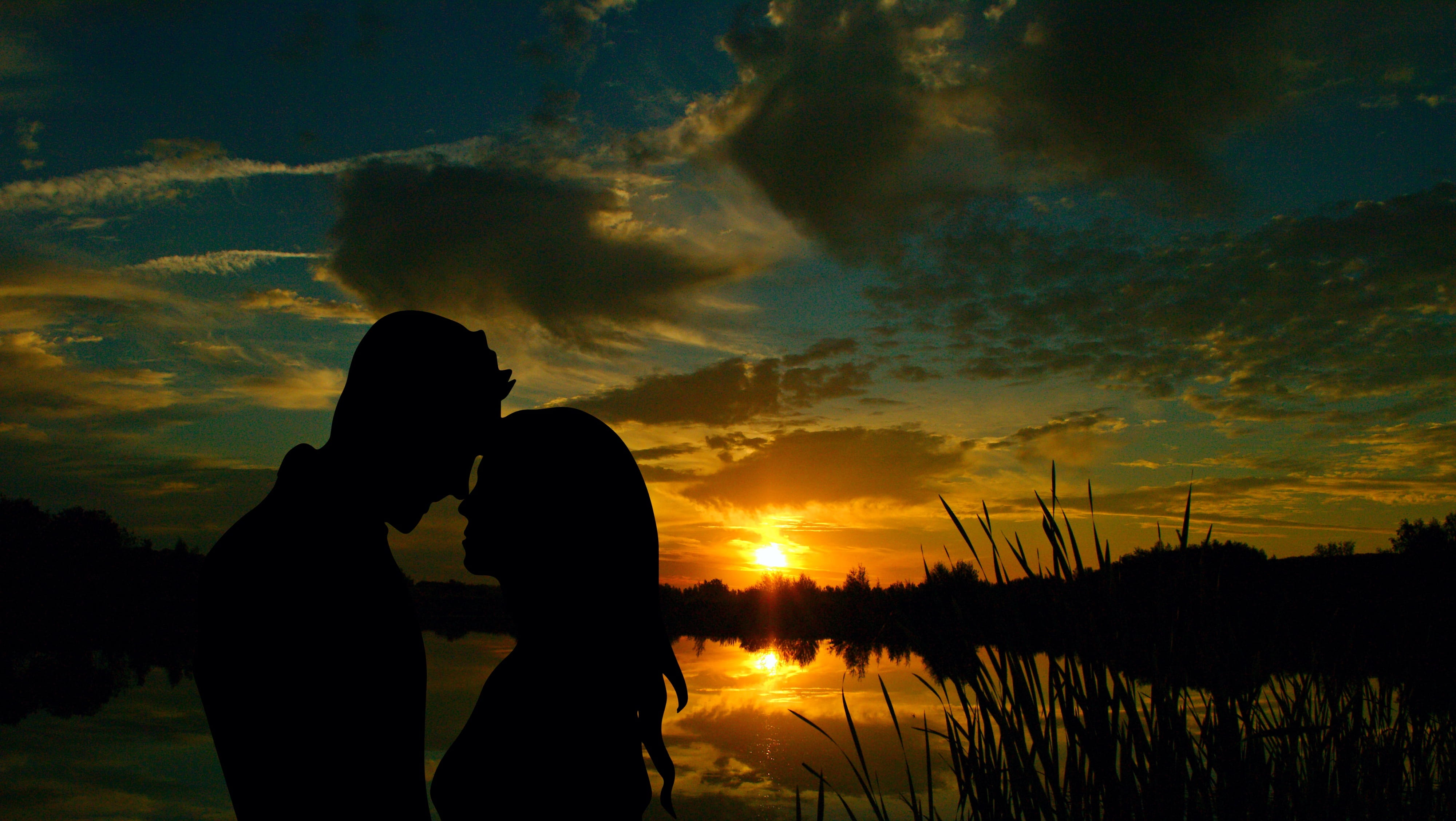 silhouette photography of man and woman beside body water 2k 4k