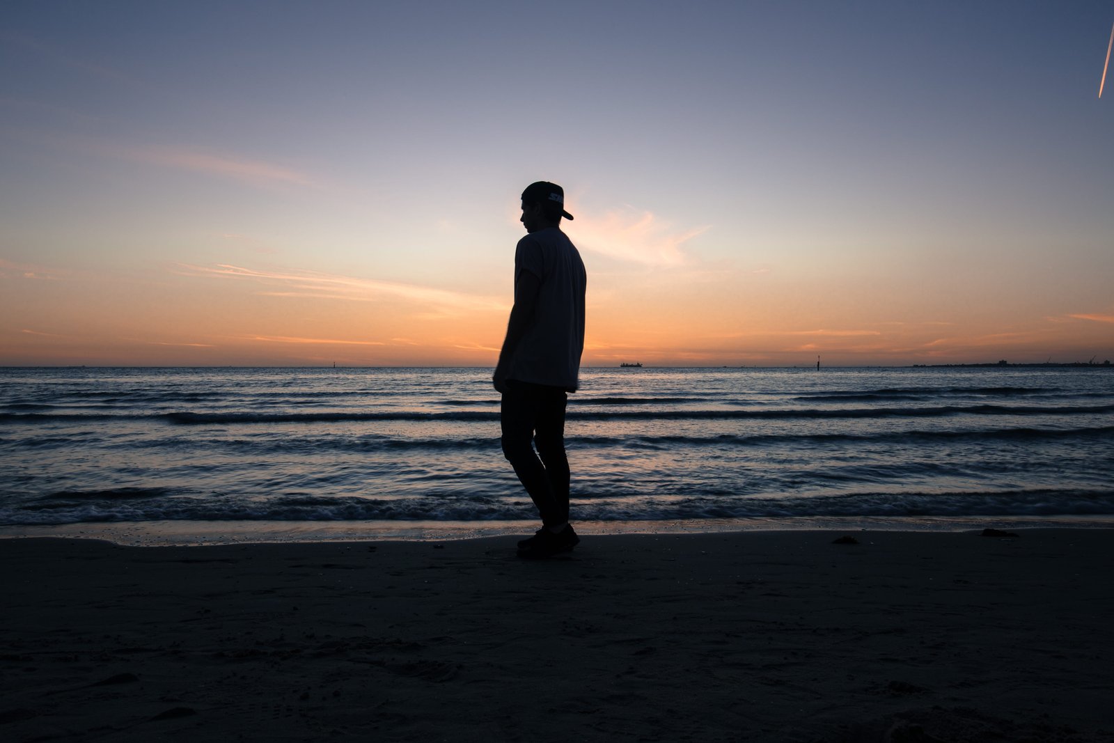 man standing on beach shore during daytime silhouette of person near ocean 2k 4k 5k