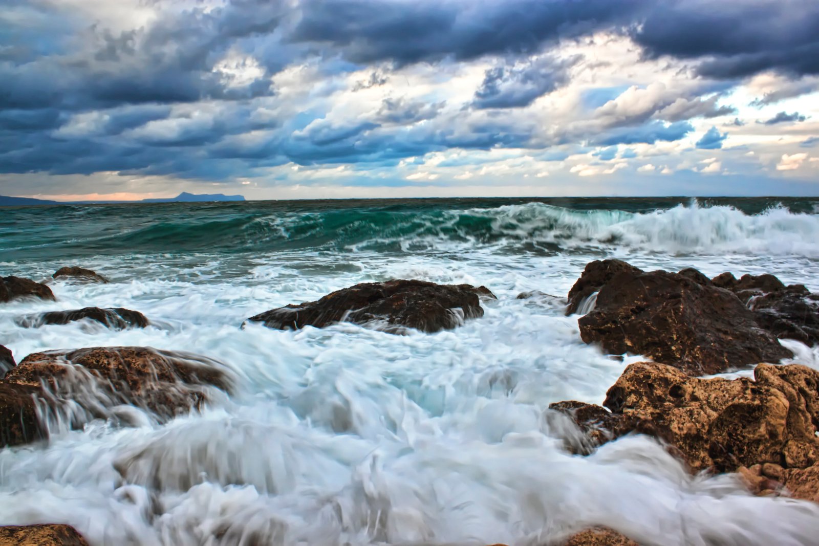photo of wave crashing in rocky beach with gray cloudy sky background 2k 4k 5k