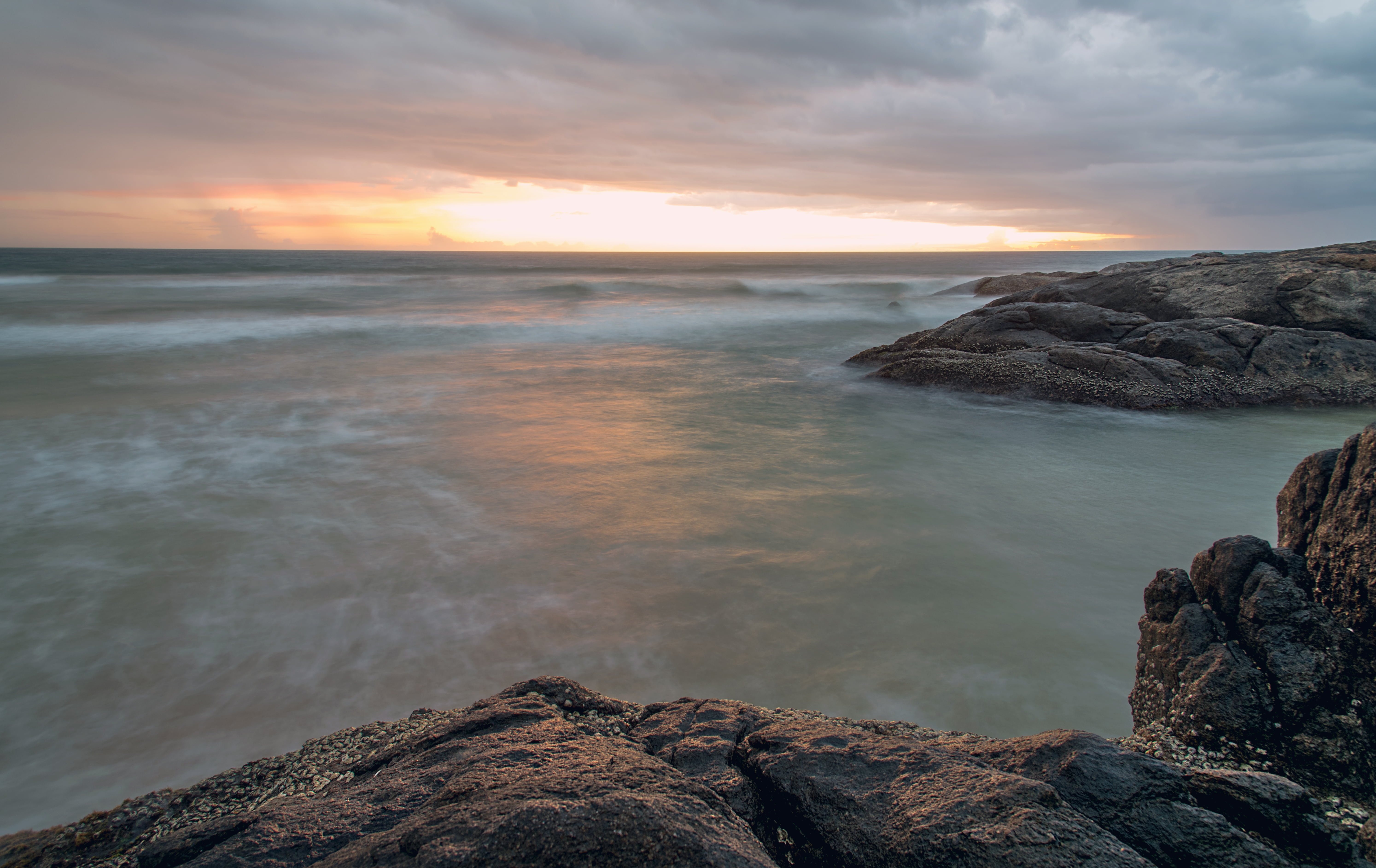 grey rock formation near beach under cloudy skies during daytime 2k 4k 5k