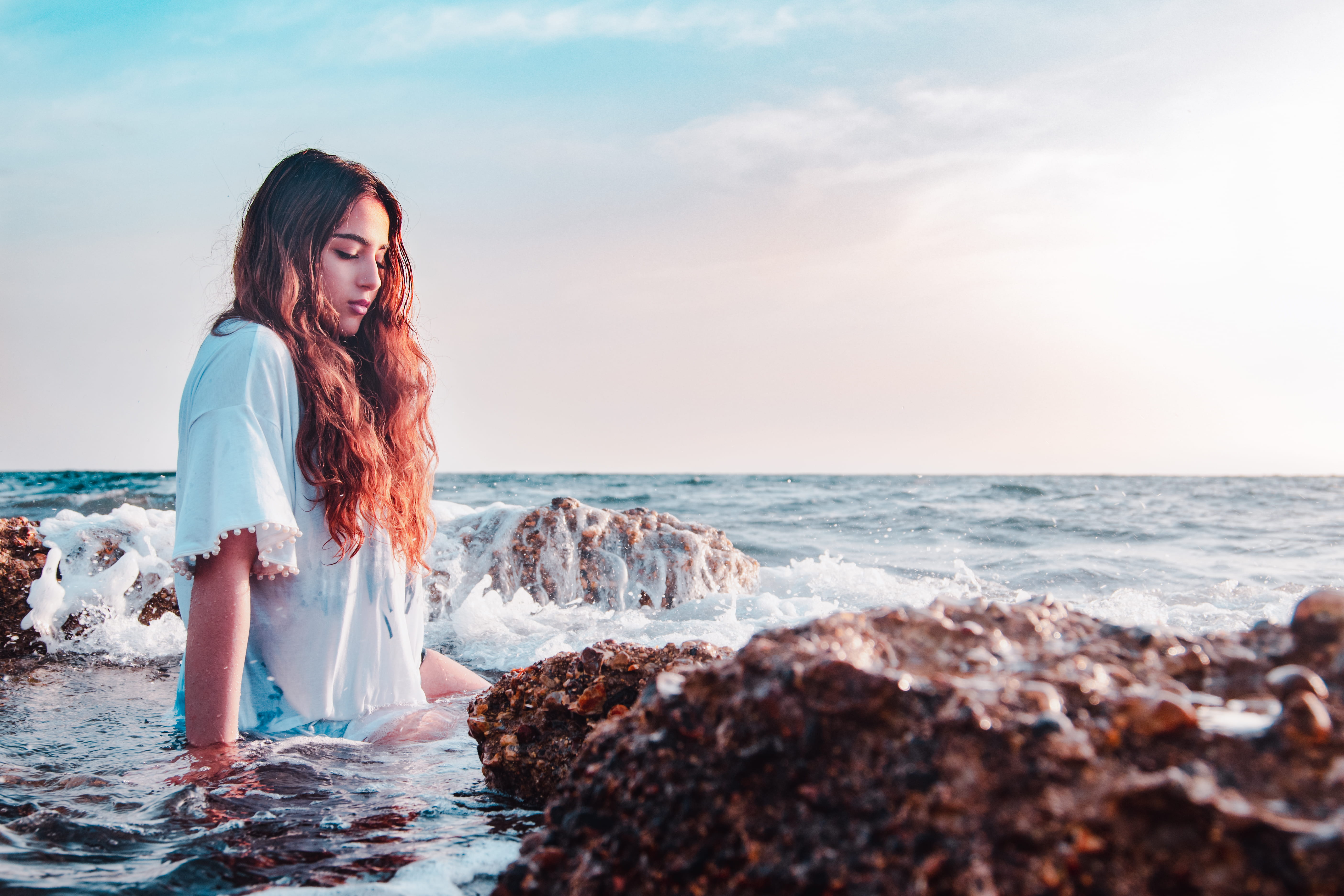 woman sitting at the rocky shore on seashore beside stones 2k 4k 5k