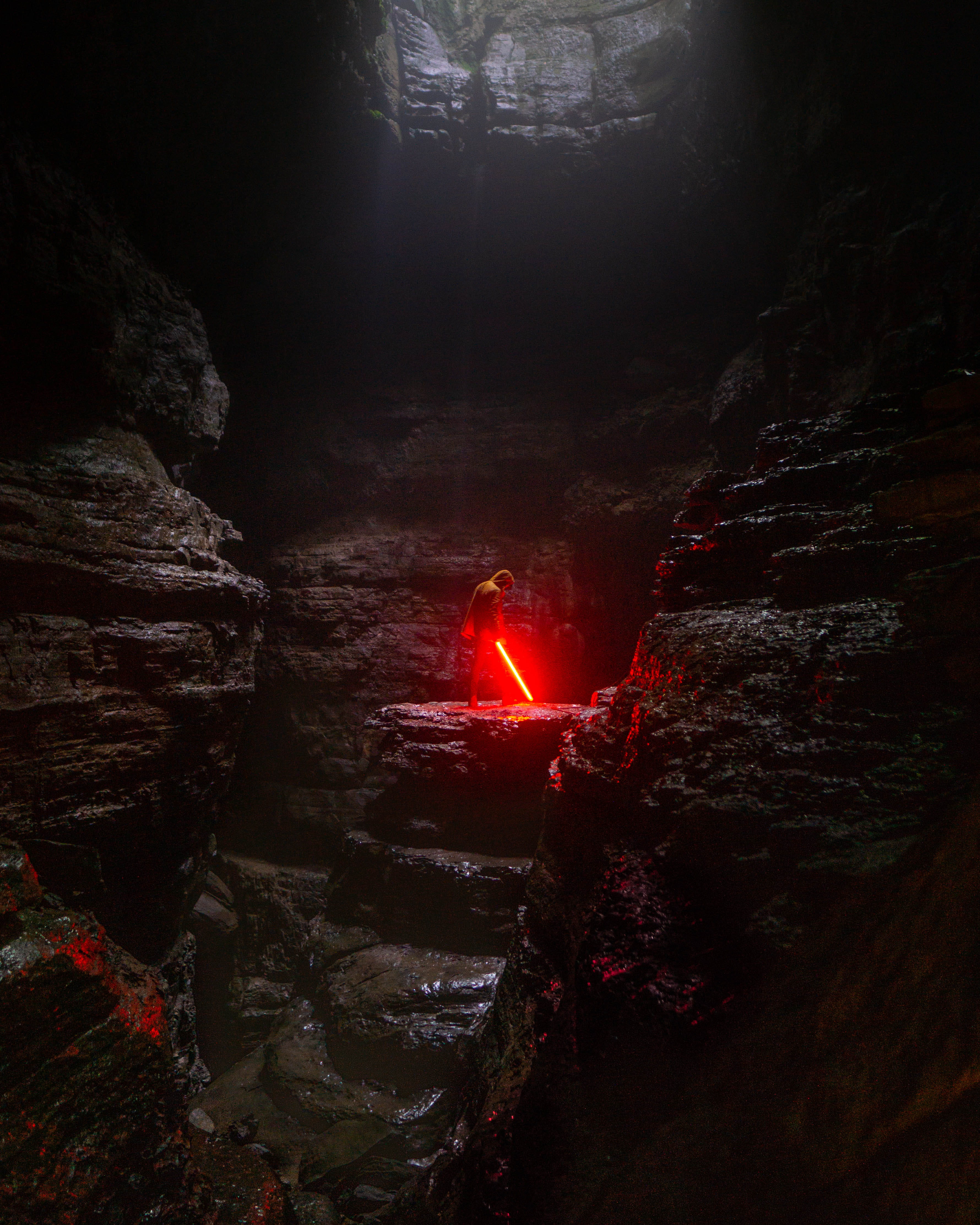 person holding red lightsaber starwars cave man moody tones 2k 4k