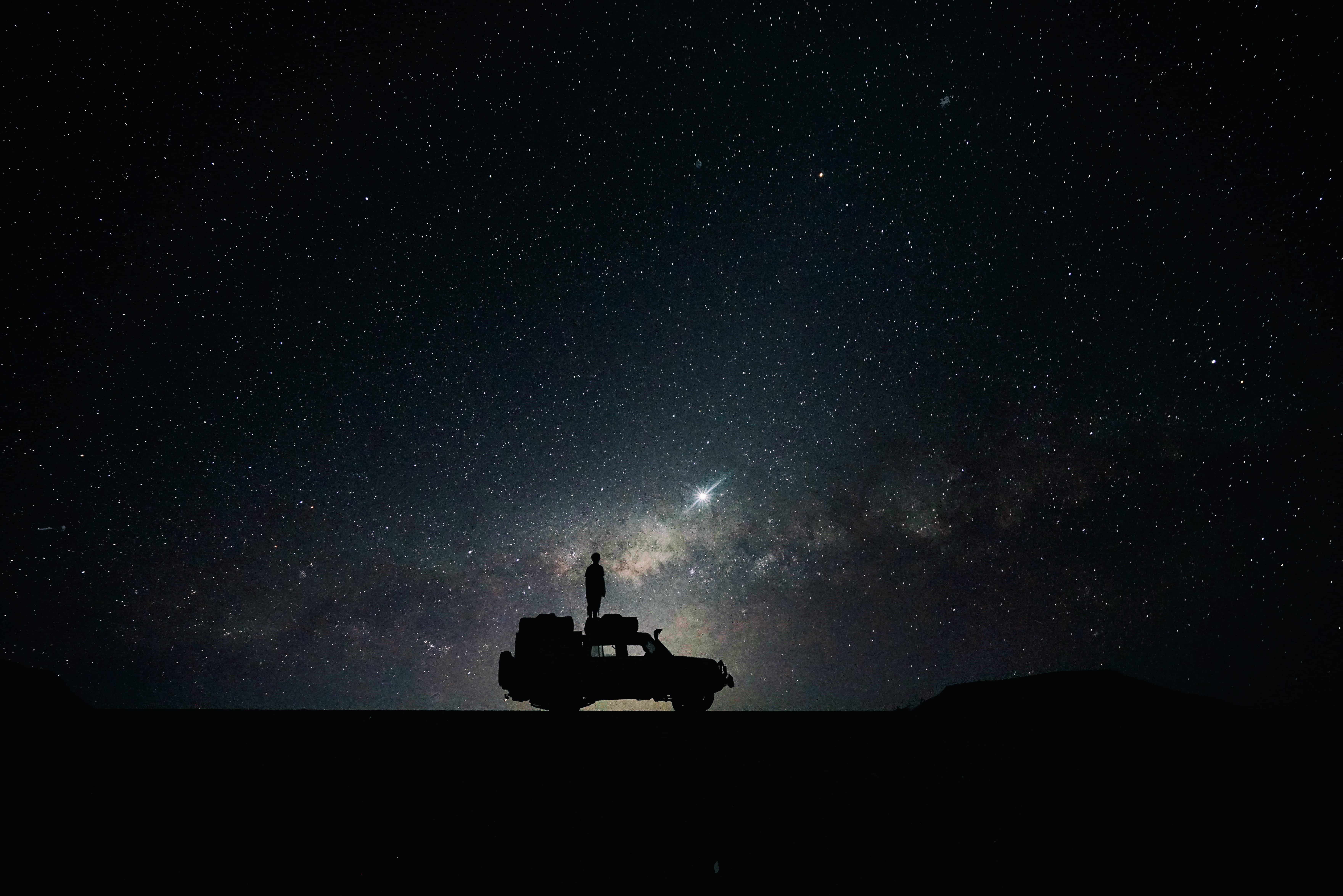 silhouette of off road car photo person standing on vehicle roof viewing starry sky during nighttime 2k 4k 5k
