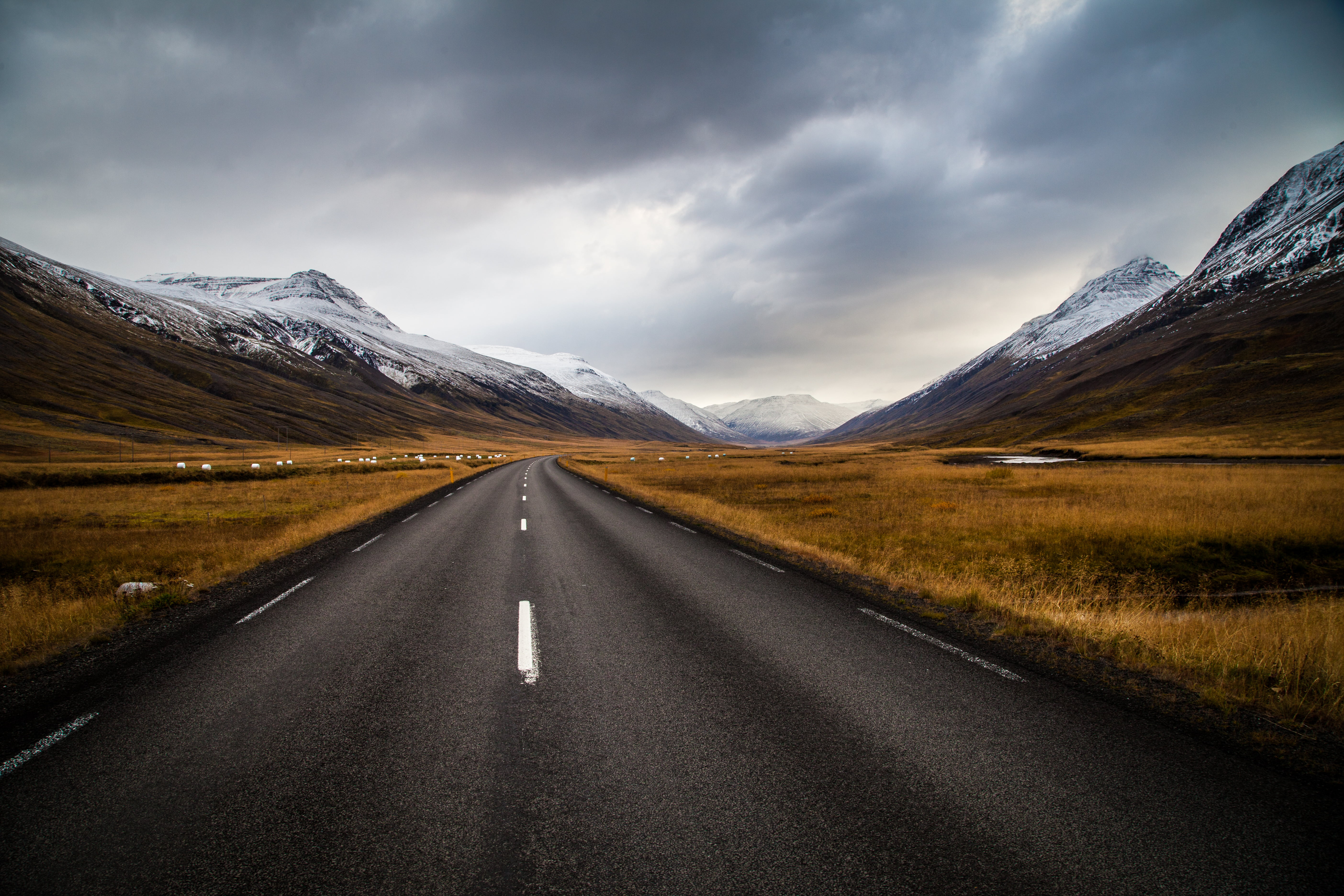 black concrete road brown grass field and white snow mountains 2k 4k 5k