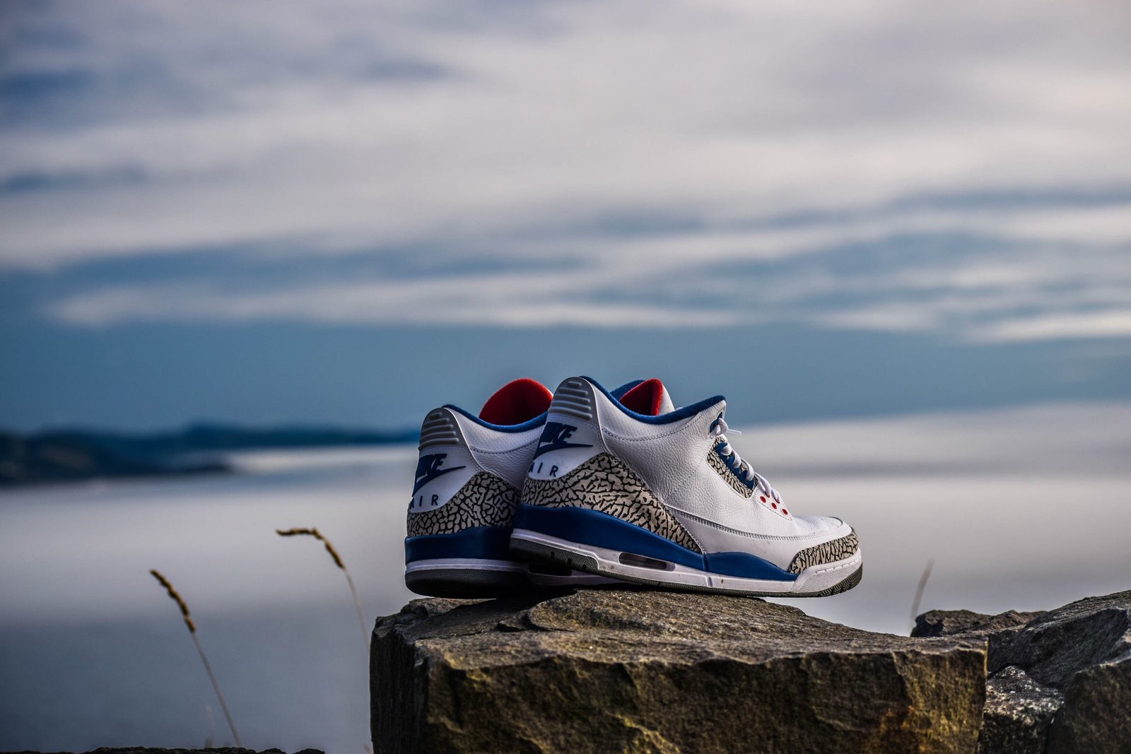 pair of white and blue Air Jordan 2 s on rock fragment black Nike shoes top at daytime 2k