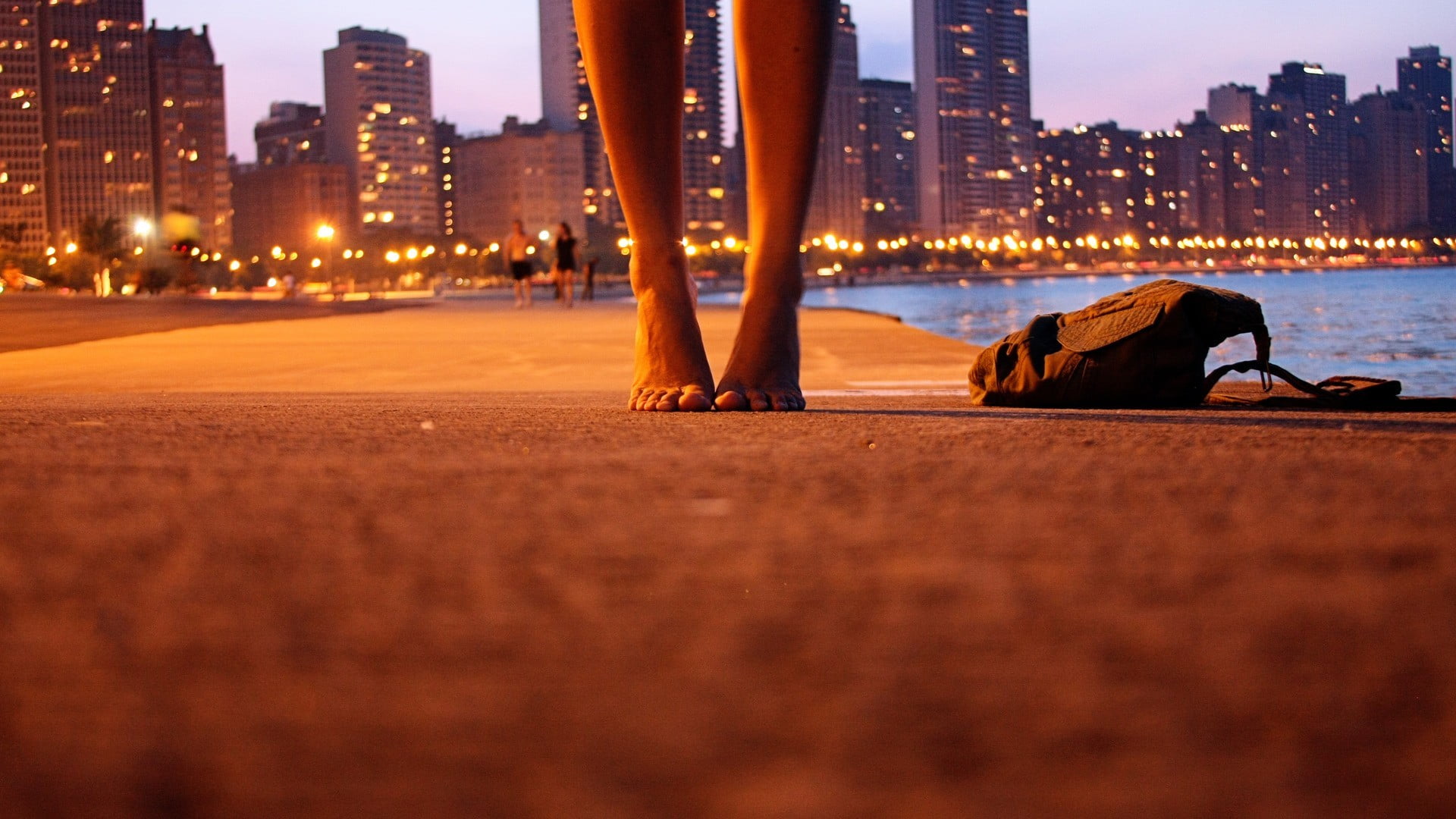 black fabric bag selective focus photography of person s feet on gray concrete pavement beside during nighttime 2k