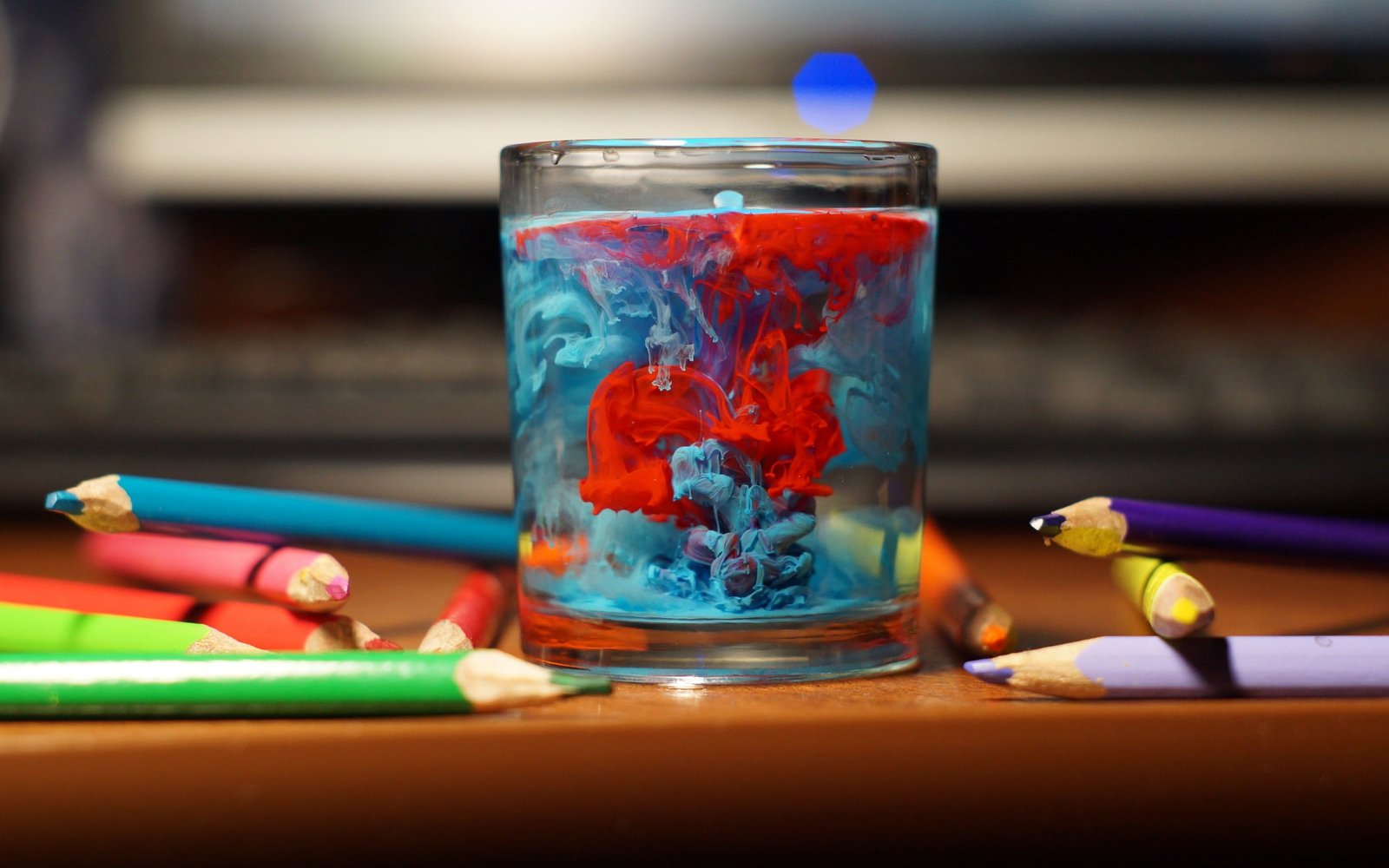 clear glass cup and assorted color pens tilt shift focus photography of drinking with red blue inside decor 2k