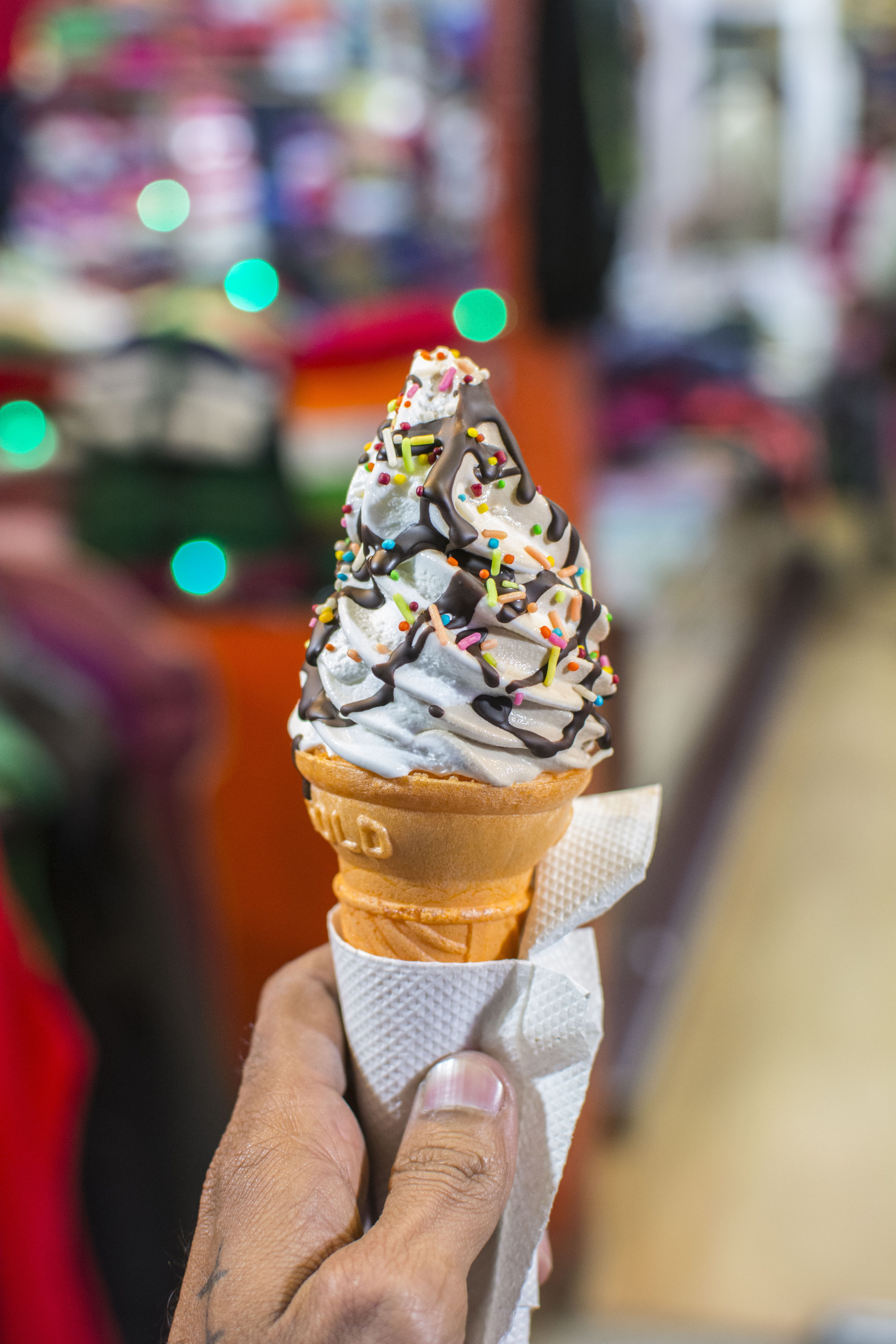 person holding wafer cone with soft served ice cream topped sprinkles and chocolate 2k 4k