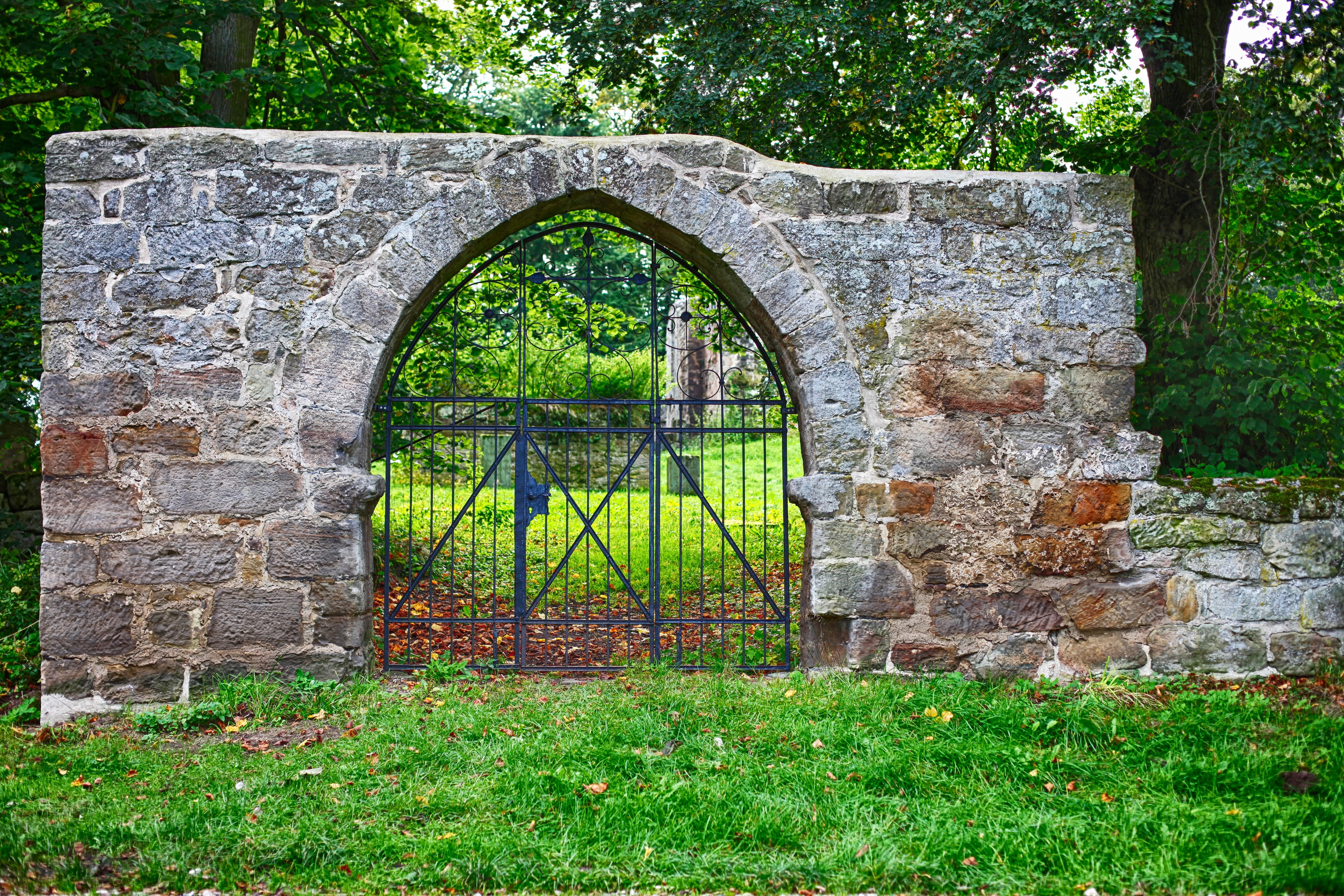 black metal gate surrounded by grass monastery old remains of a wall 2k 4k 5k