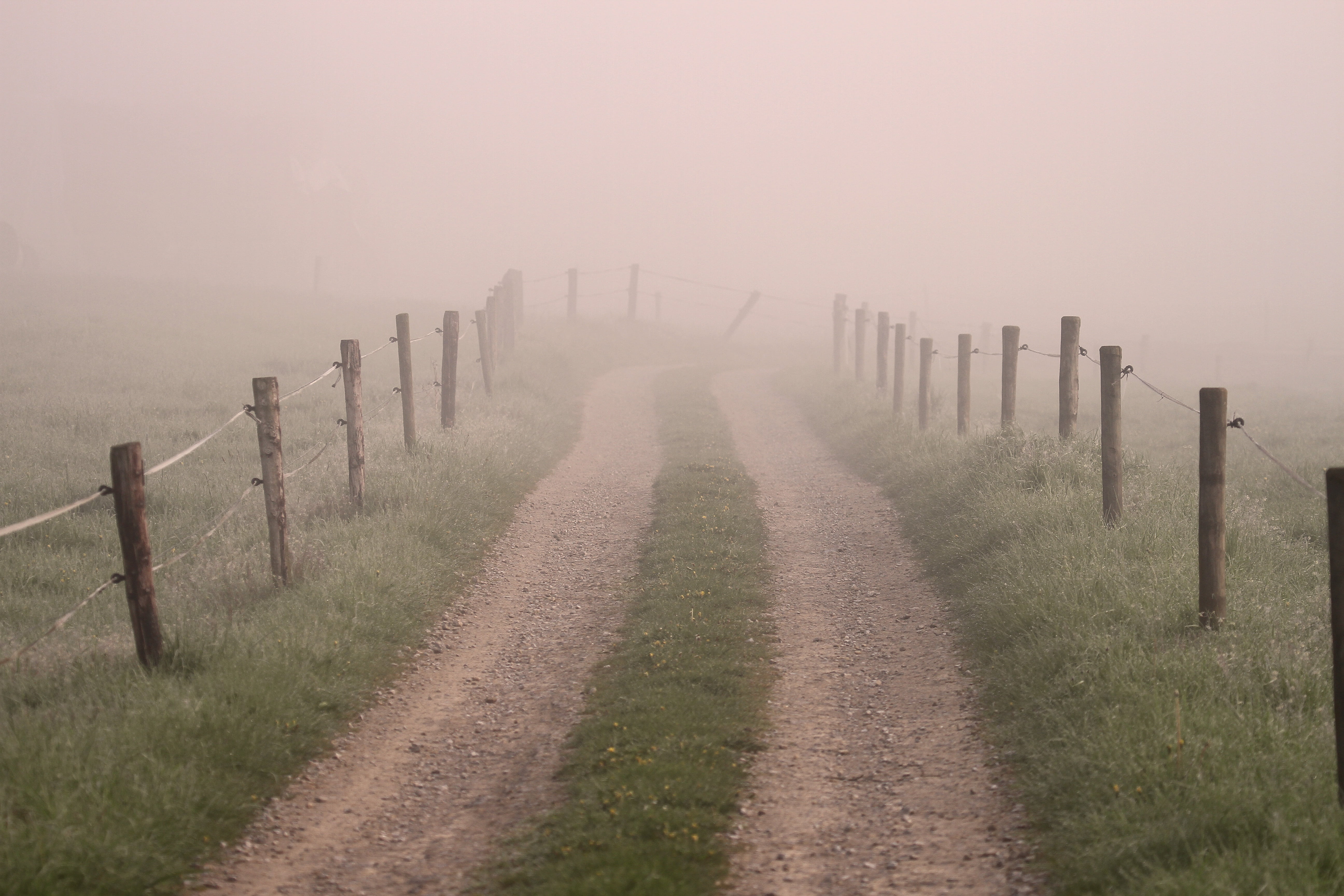 landscape photo of dirt road with brown wood posts by the under foggy sky 2k 4k 5k