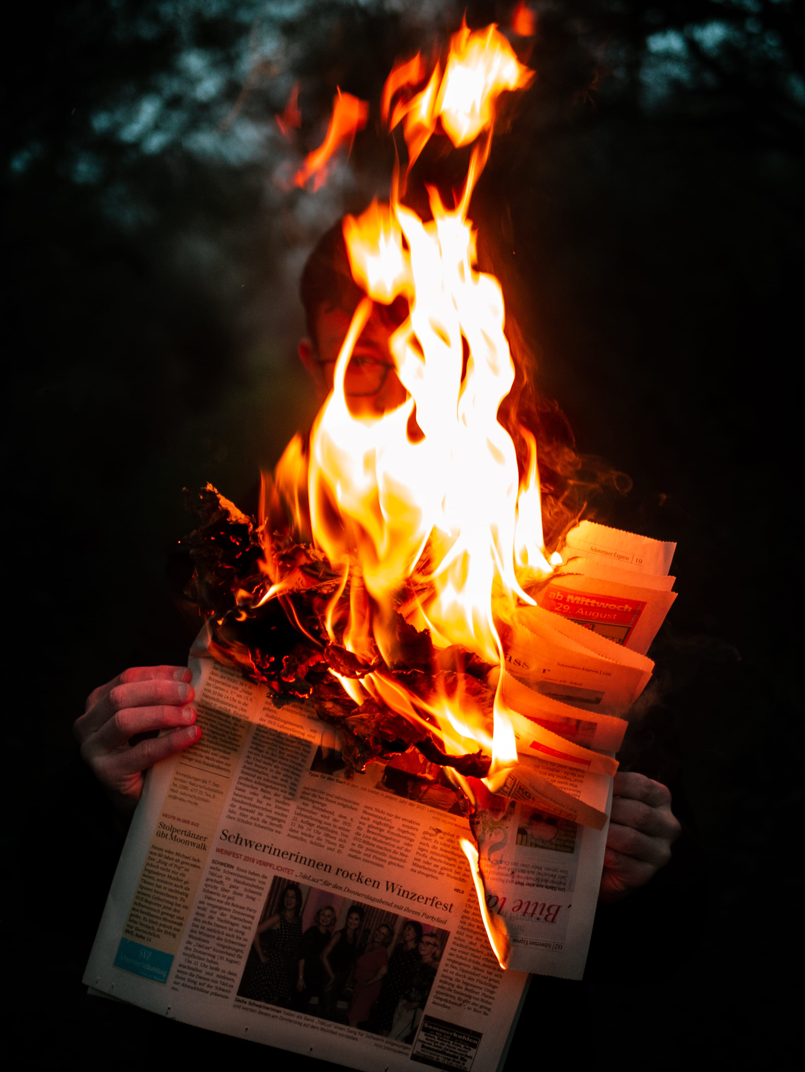 person holding burning newspaper fire flame bonfire text 2k