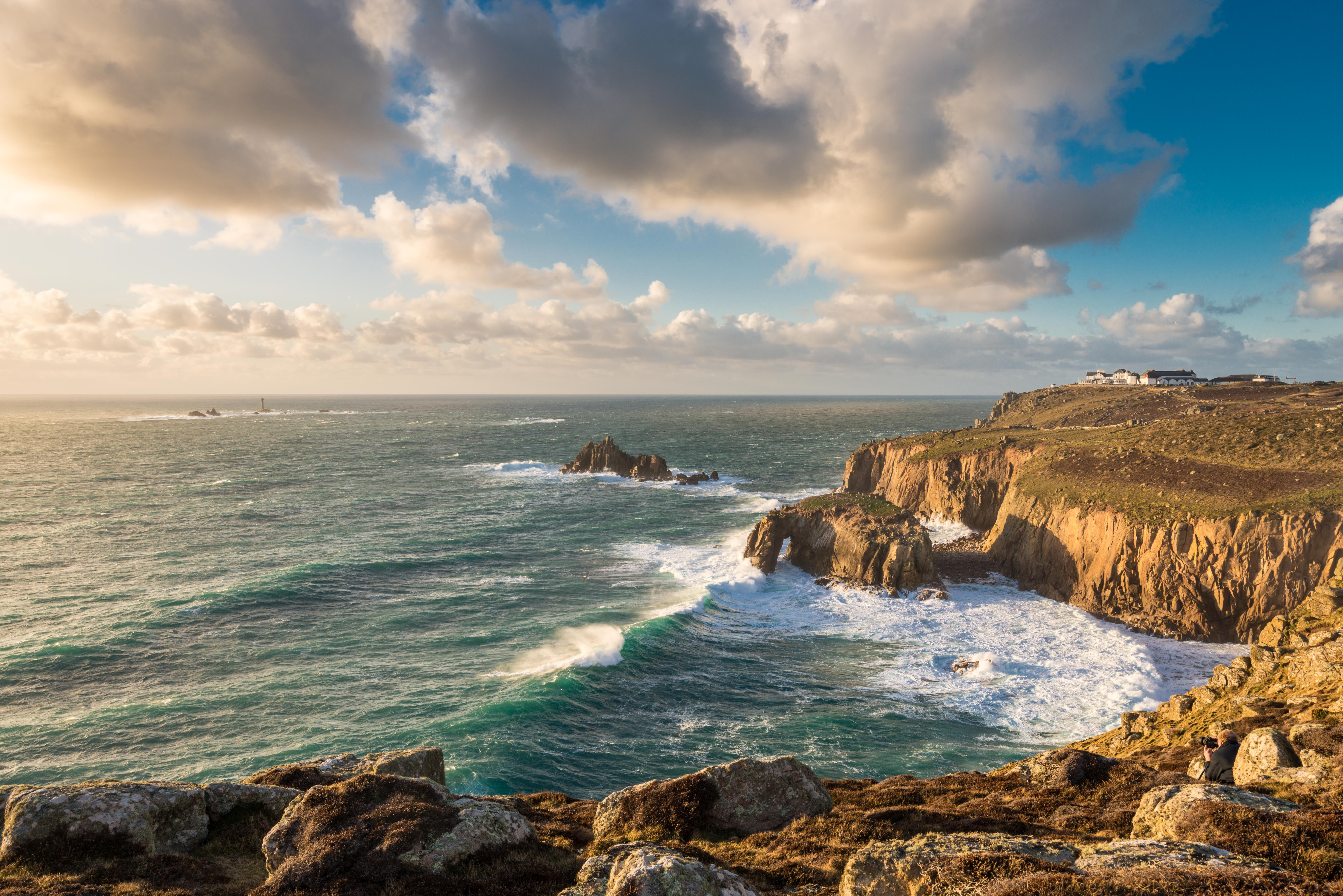 brown mountains and rock formation near sea with blue sky white clouds 2k 4k 5k